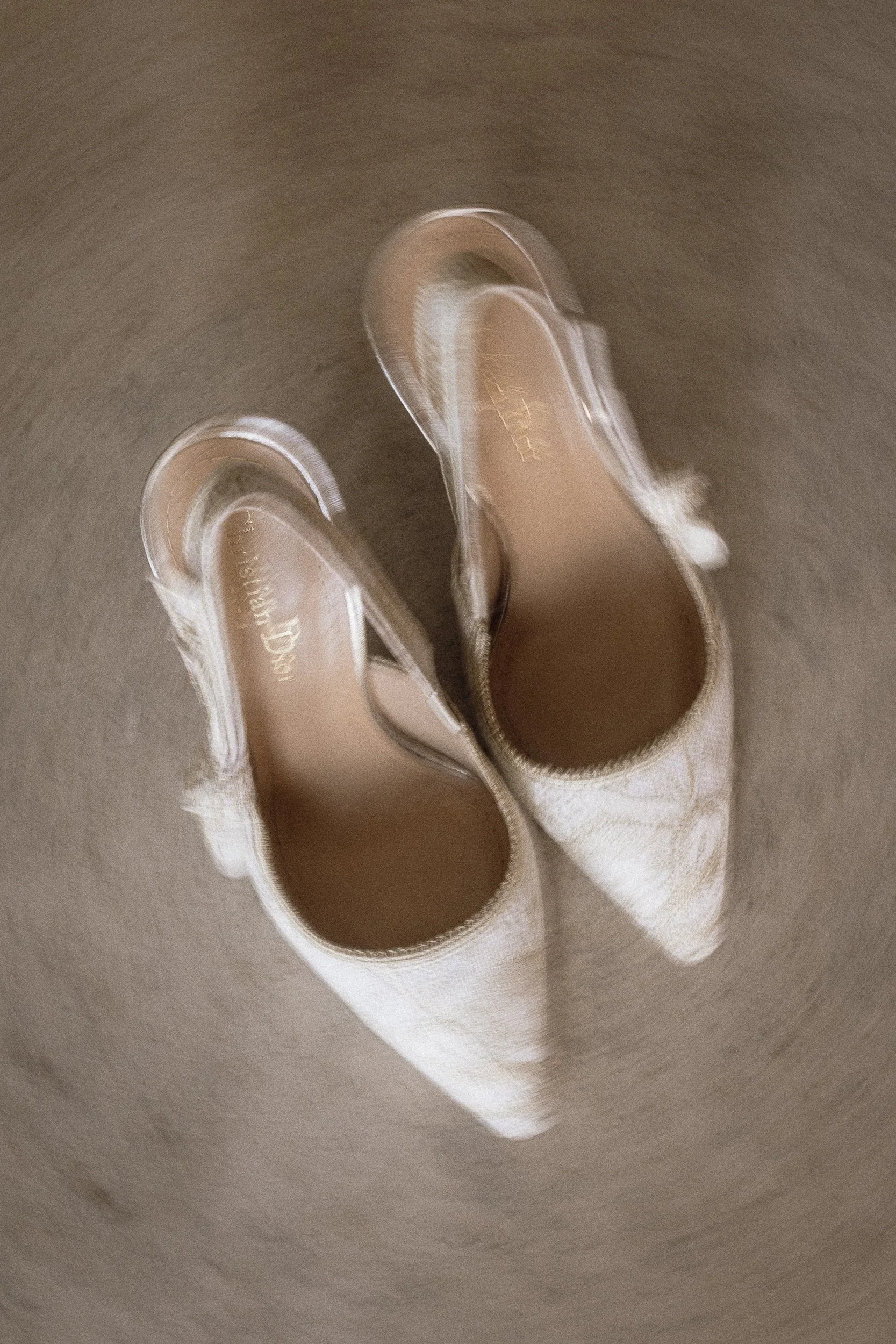 A pair of beige sneakers hanging inside a toilet bowl with water.