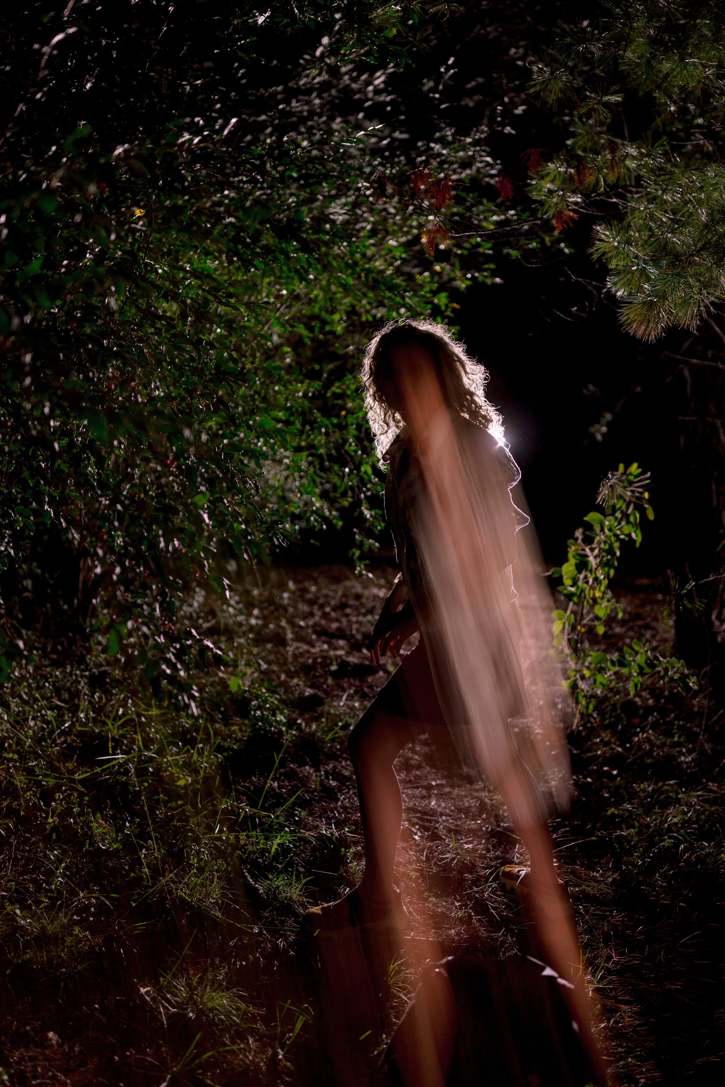 Shaman moving forward in the night with a glowing light around her that looks like wings