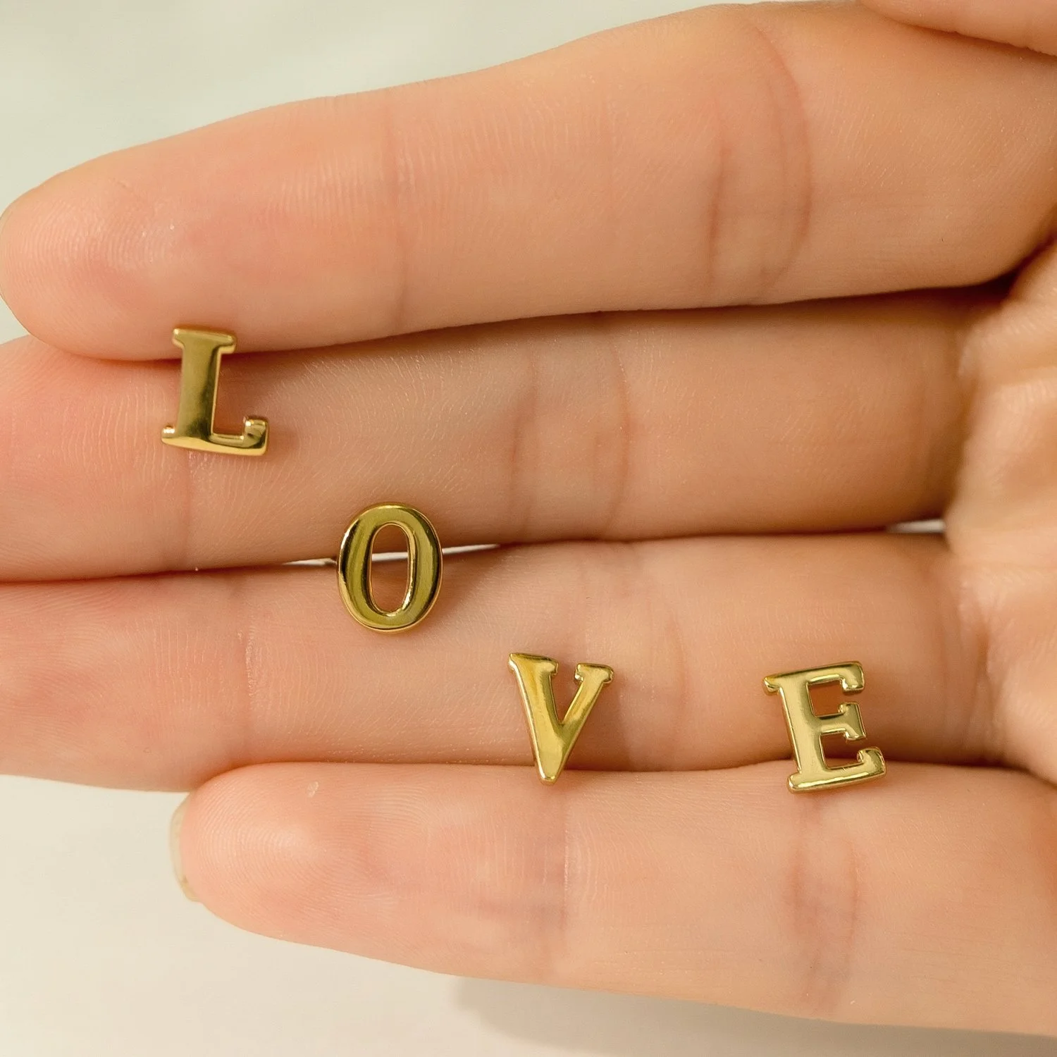 Gold letter rings spell out the word 'LOVE' on a person's fingers.
