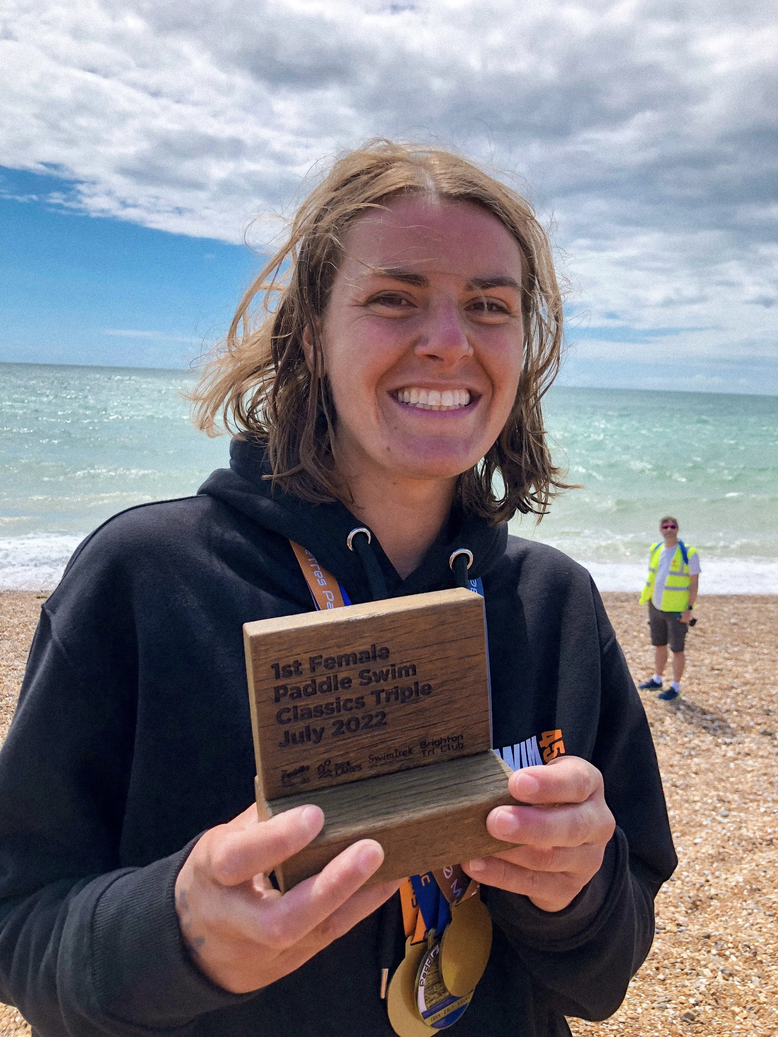 Laura celebrating a Triple Crown swim win on a beach in Hove