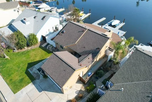 Aerial view of waterfront homes with boats on a calm river.