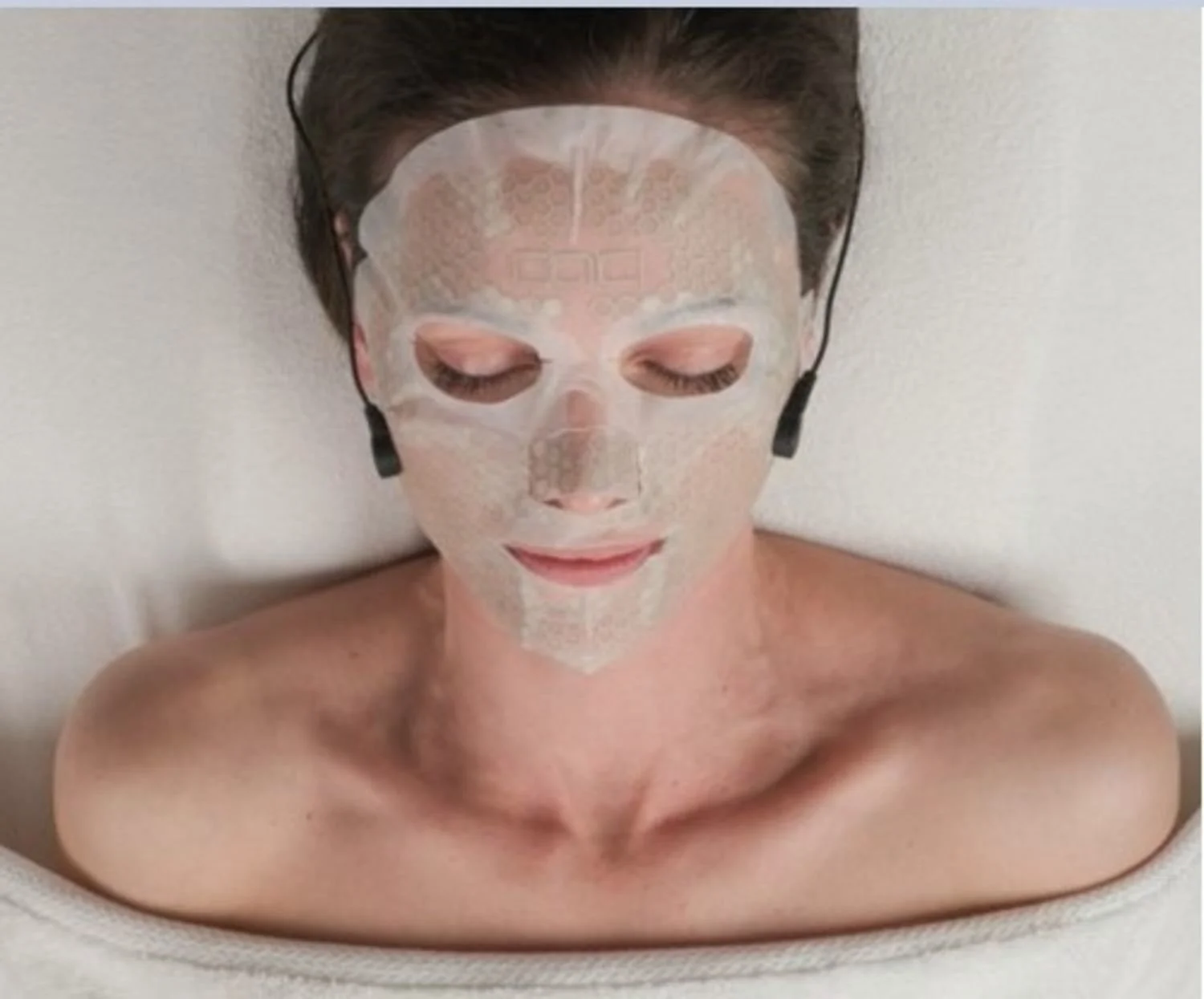 lady lying on a beauty bed with the CACI microcurrent mask on