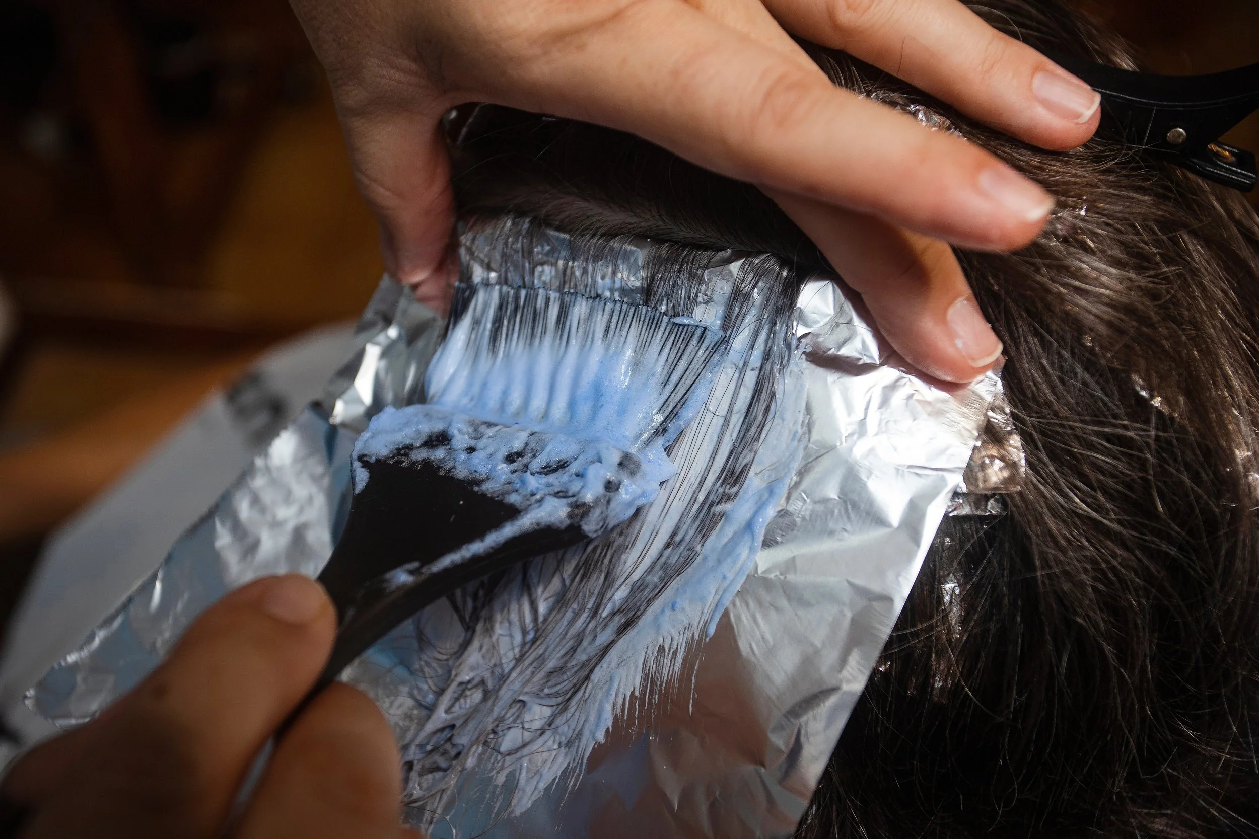 Hair being dyed with blue hair color and foil