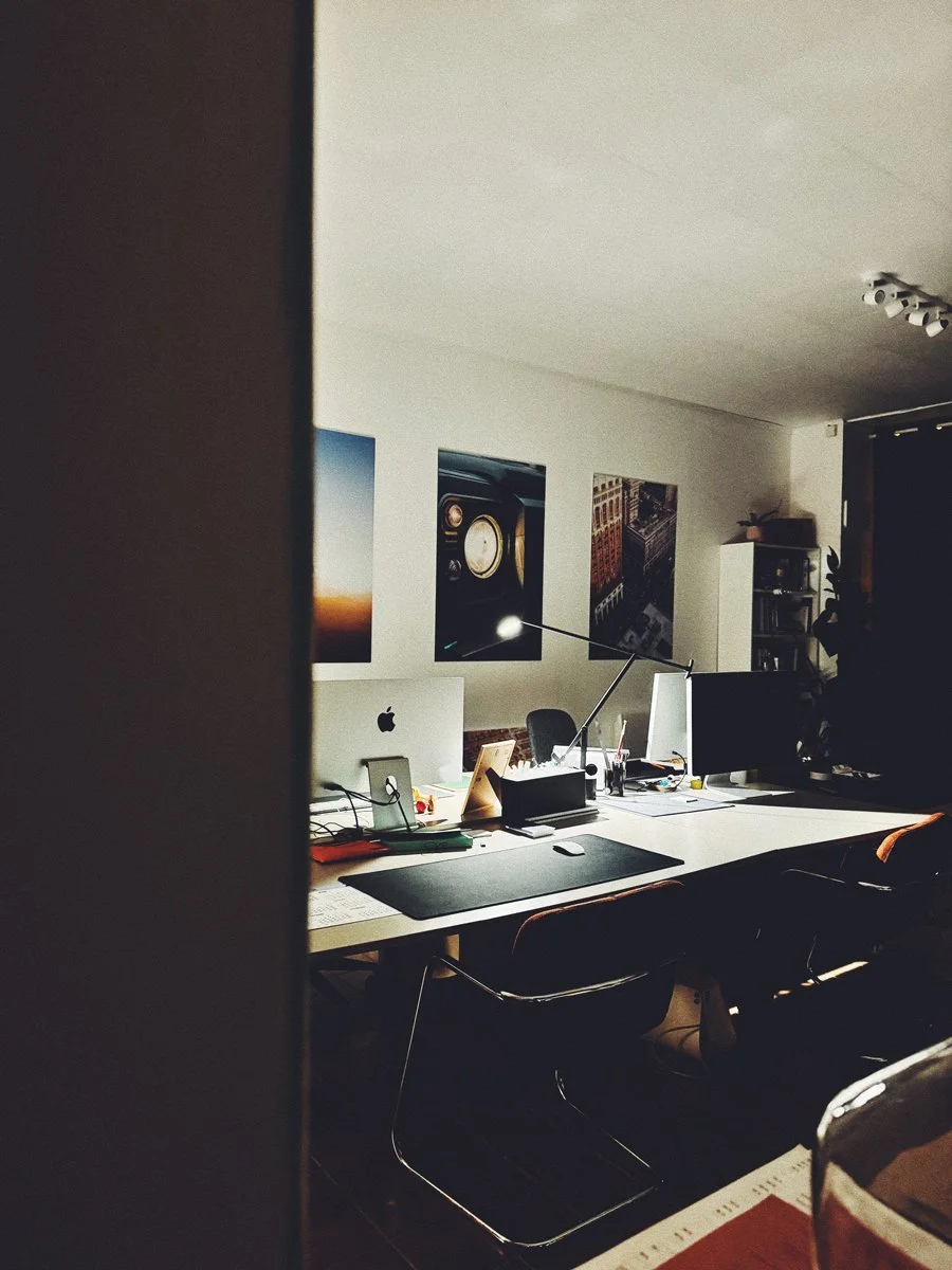 Bureau moderne avec ordinateurs, lampe de bureau et affiches murales.