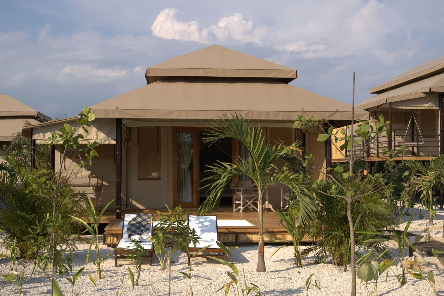 Luxury tent village pavilion with lush landscaping and palm trees.