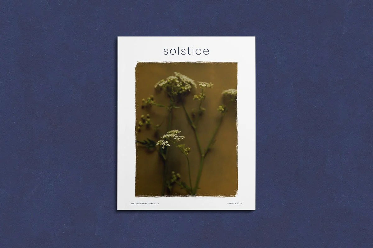 Cover of a magazine titled 'solstice' featuring a close-up photograph of wildflowers. The magazine is placed on a dark blue surface.