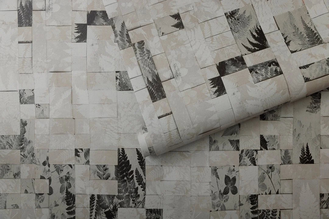 An unfurled roll of wallcovering with a woven botanical pattern.