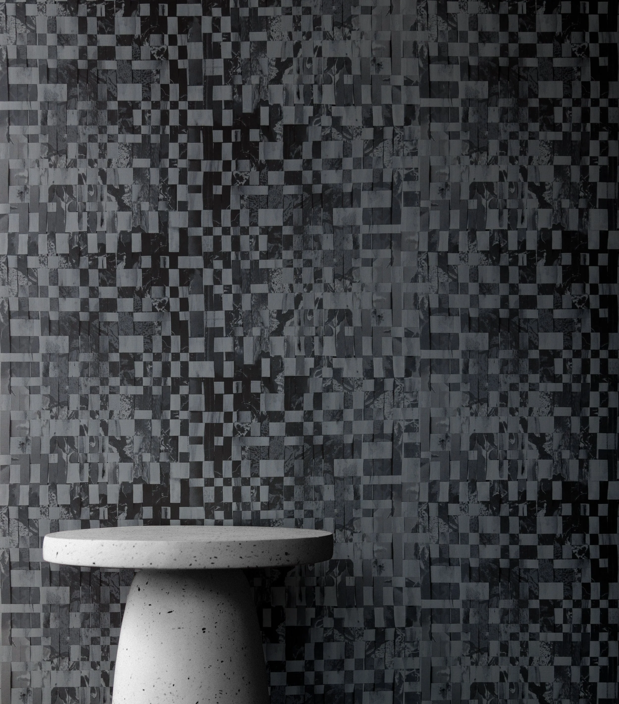 A white stone end table in front of deep blue woven wallpaper.