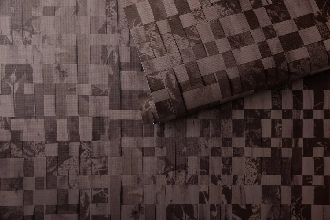 A roll of wallpaper featuring a dark burgundy design with a woven pattern.