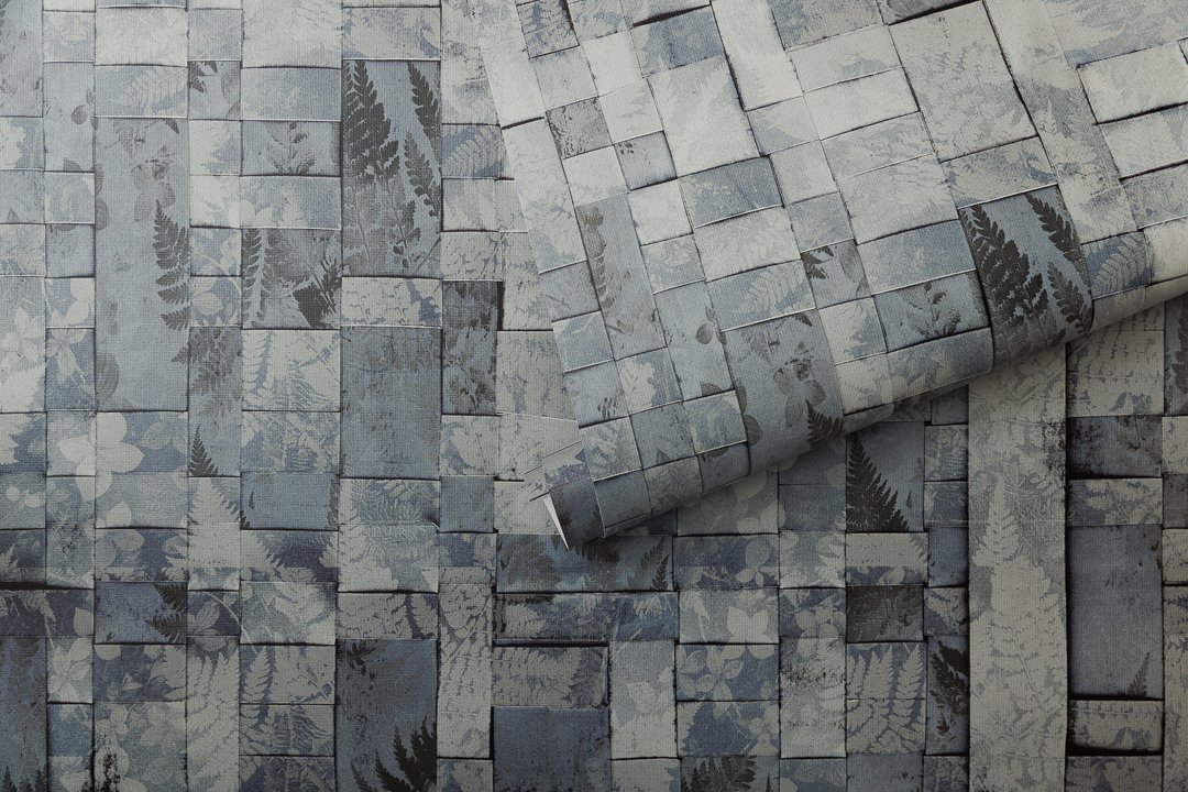 An unfurled roll of wallcovering with a woven botanical pattern.