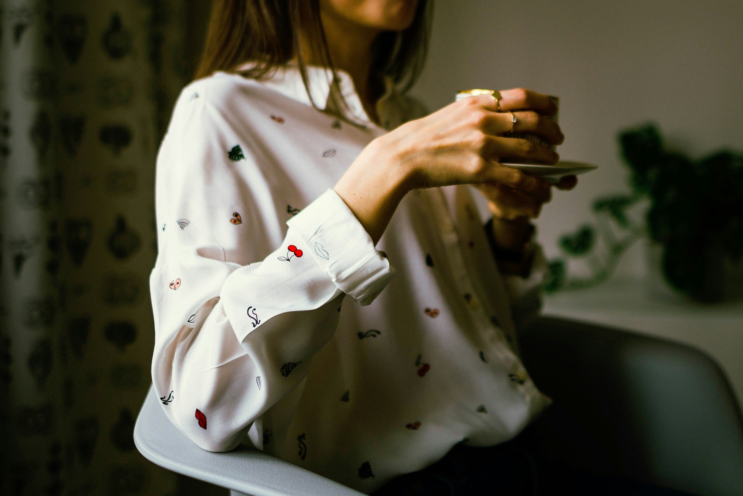 woman in a dress shirt drinking coffee in a relaxed manner with a saucer