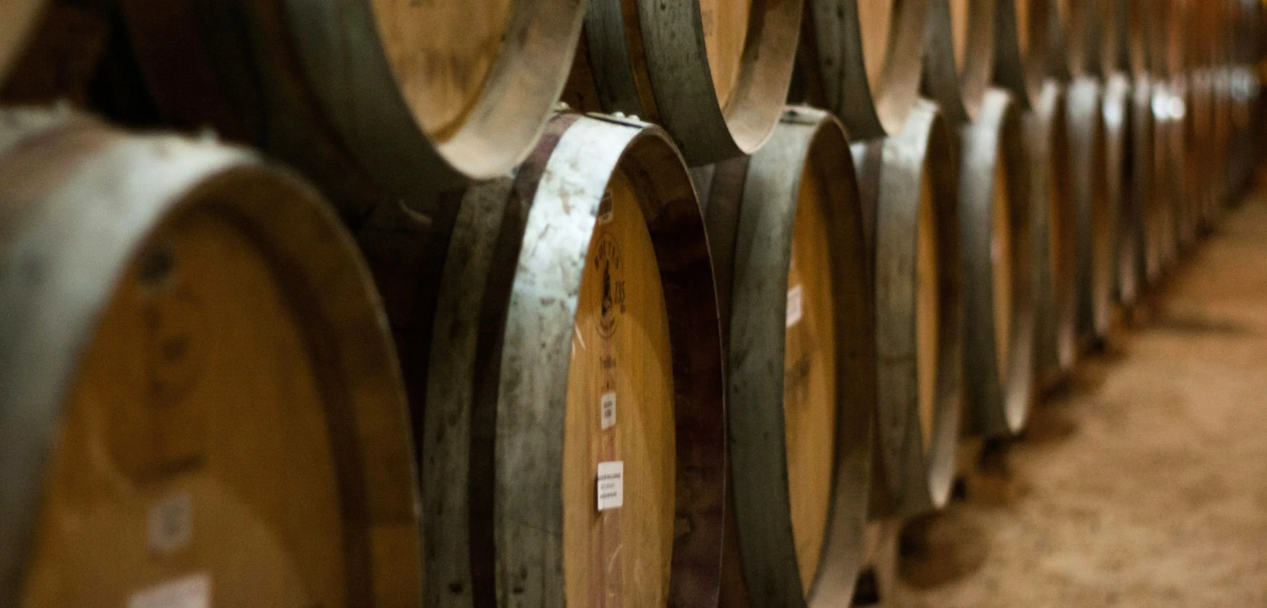 A row of wooden wine barrels stacked in a cellar, showcasing the craftsmanship and aging process of fine wines.