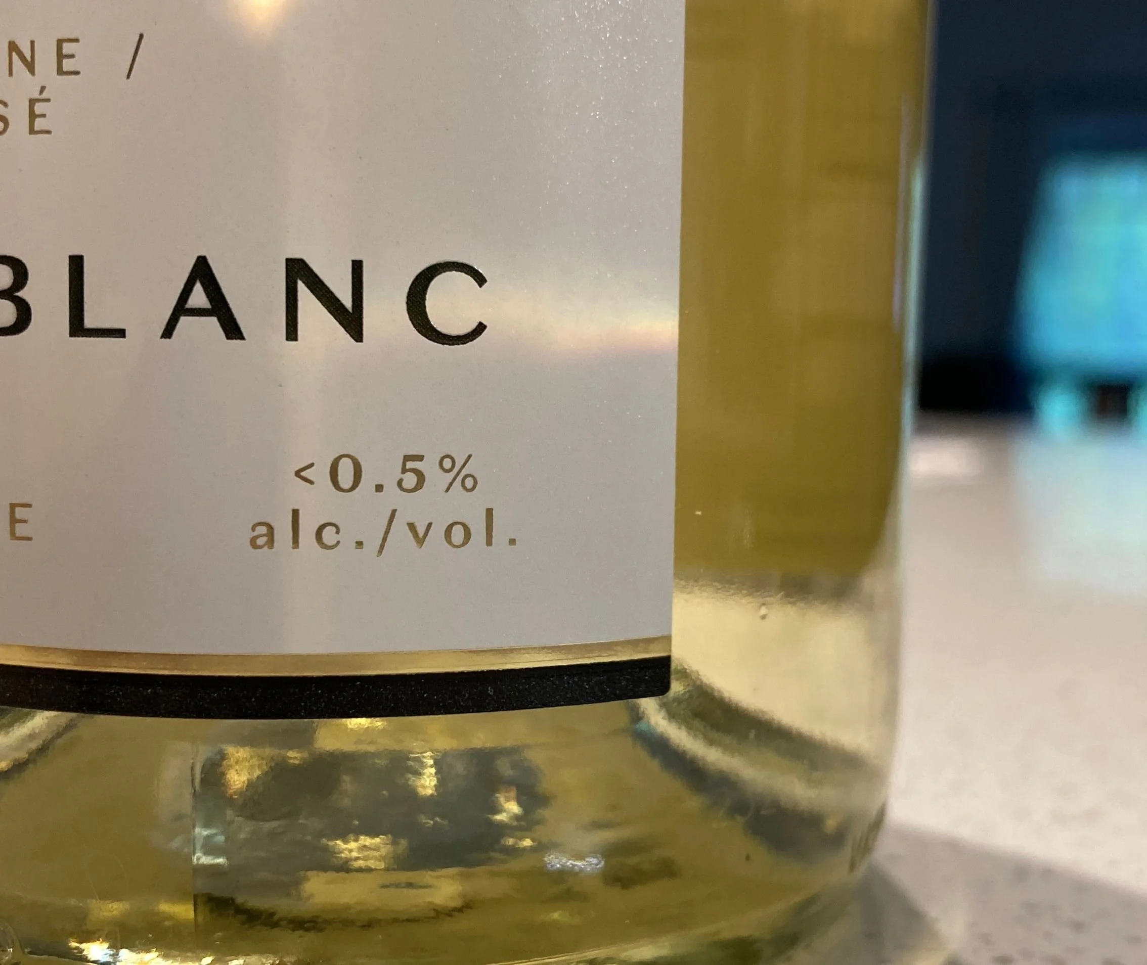 Close-up of a white wine bottle label featuring the name 'Blanc' and indicating less than 0.5% alcohol by volume.
