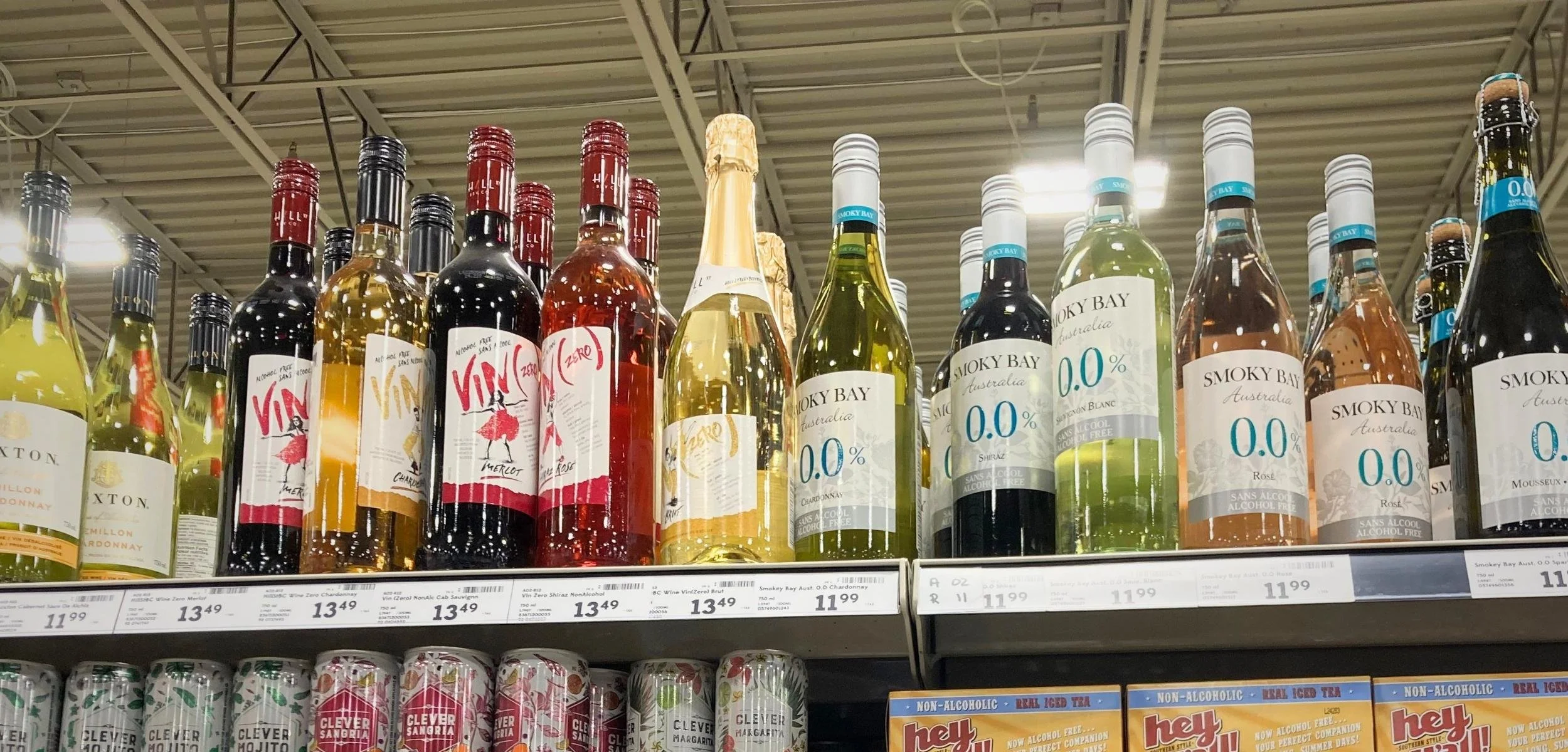 A variety of wine bottles displayed on a store shelf, including non-alcoholic options and different wine types.
