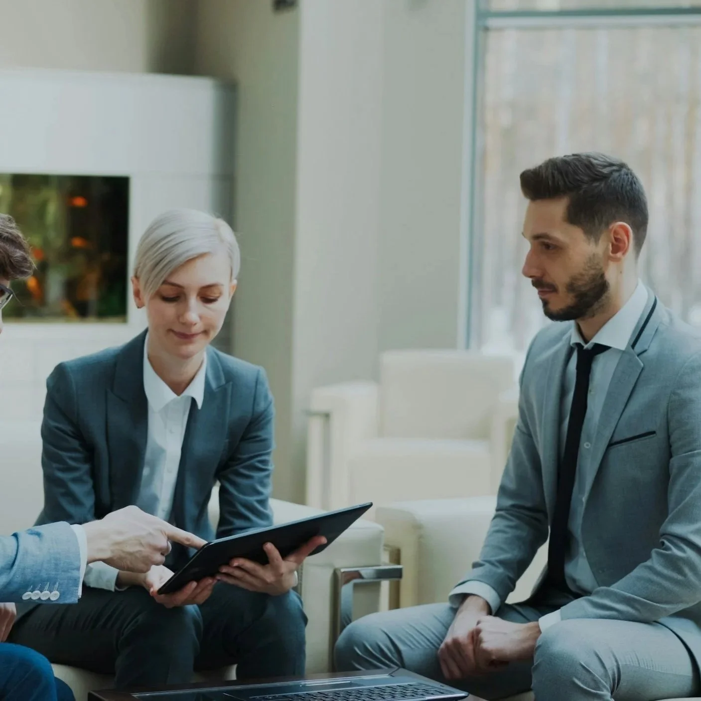 Business professionals in a meeting room reviewing documents on a tablet.