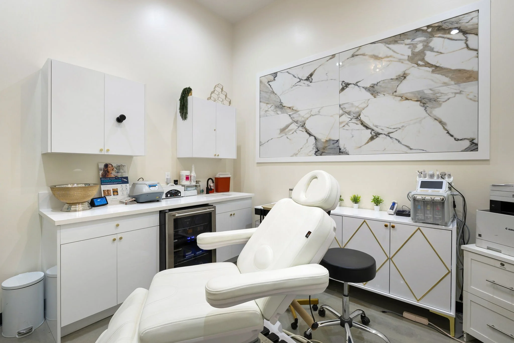 Medical treatment room with a white reclining chair, white cabinets, and medical gadgets.