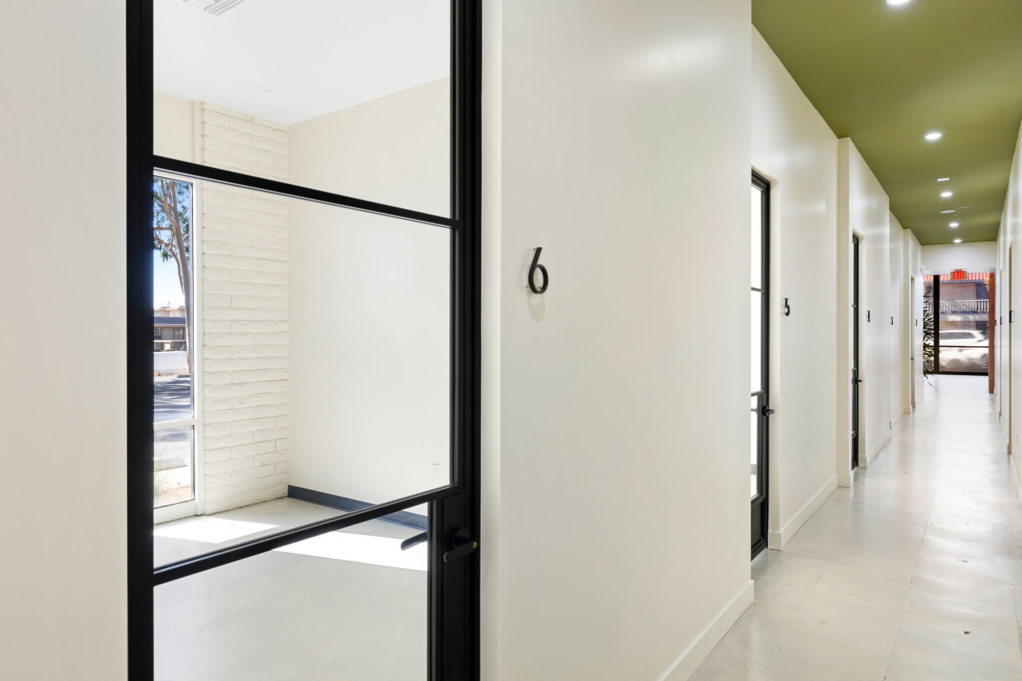 Modern hallway with numbered doors and green ceiling