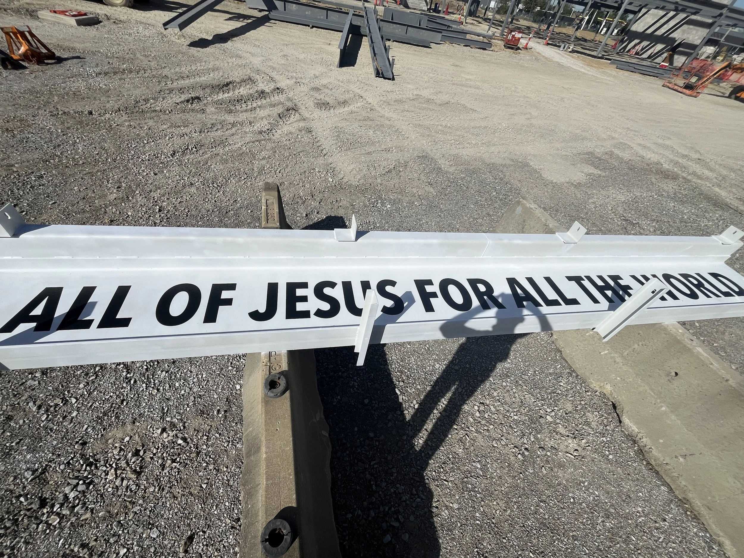 Steel beam on the ground with the phrase ‘All of Jesus for All the World’ painted on it.