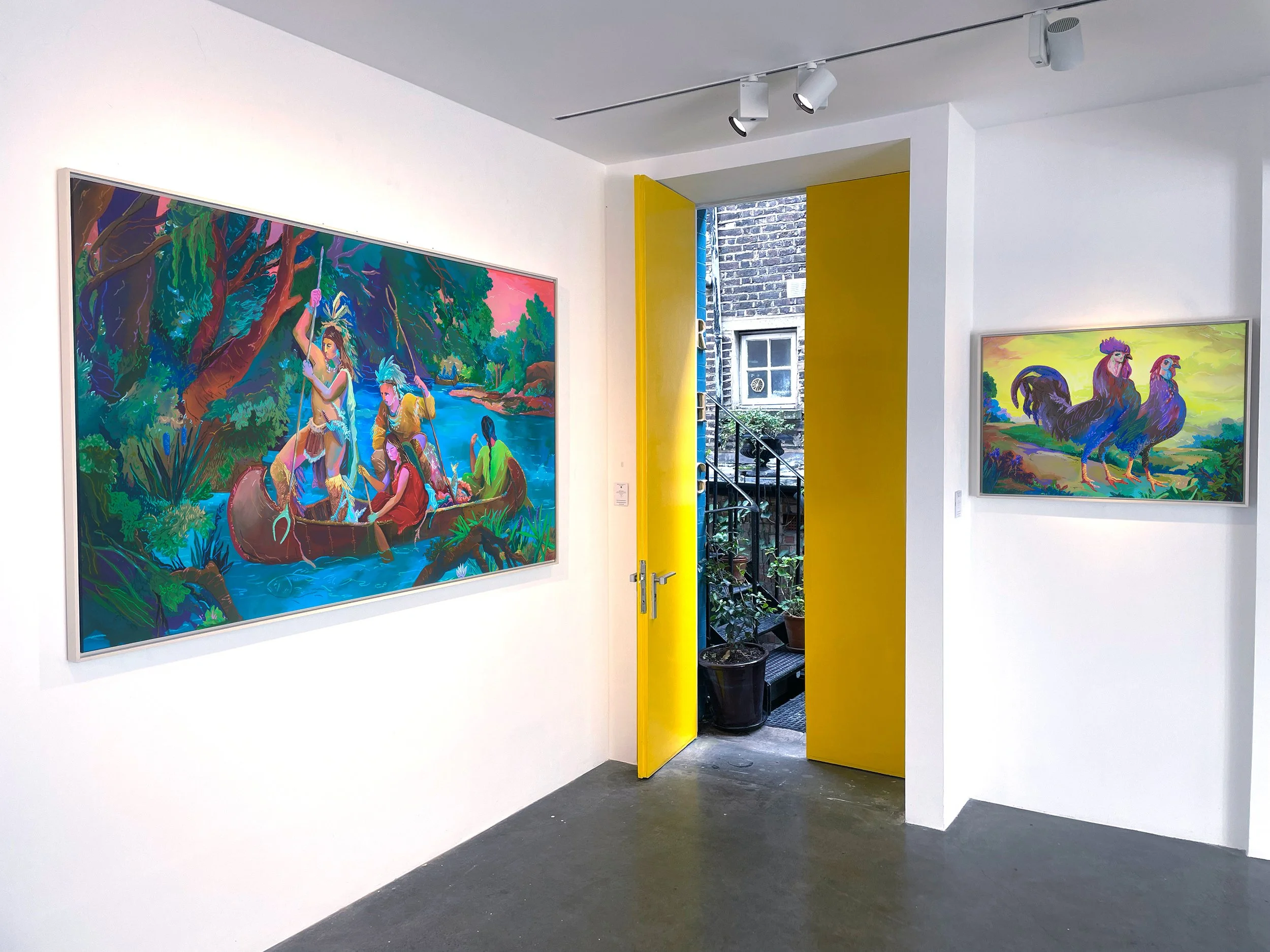 Colorful paintings displayed on white gallery walls with a yellow door open to an outdoor staircase and plants.