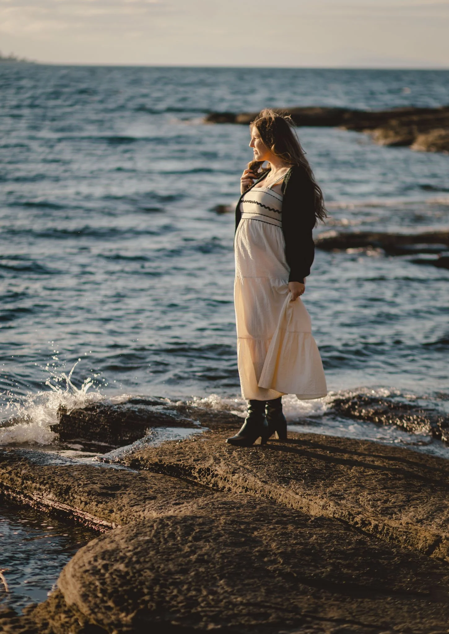 A woman poses at sunset on the rocky beach for maternity photos in Nanaimo