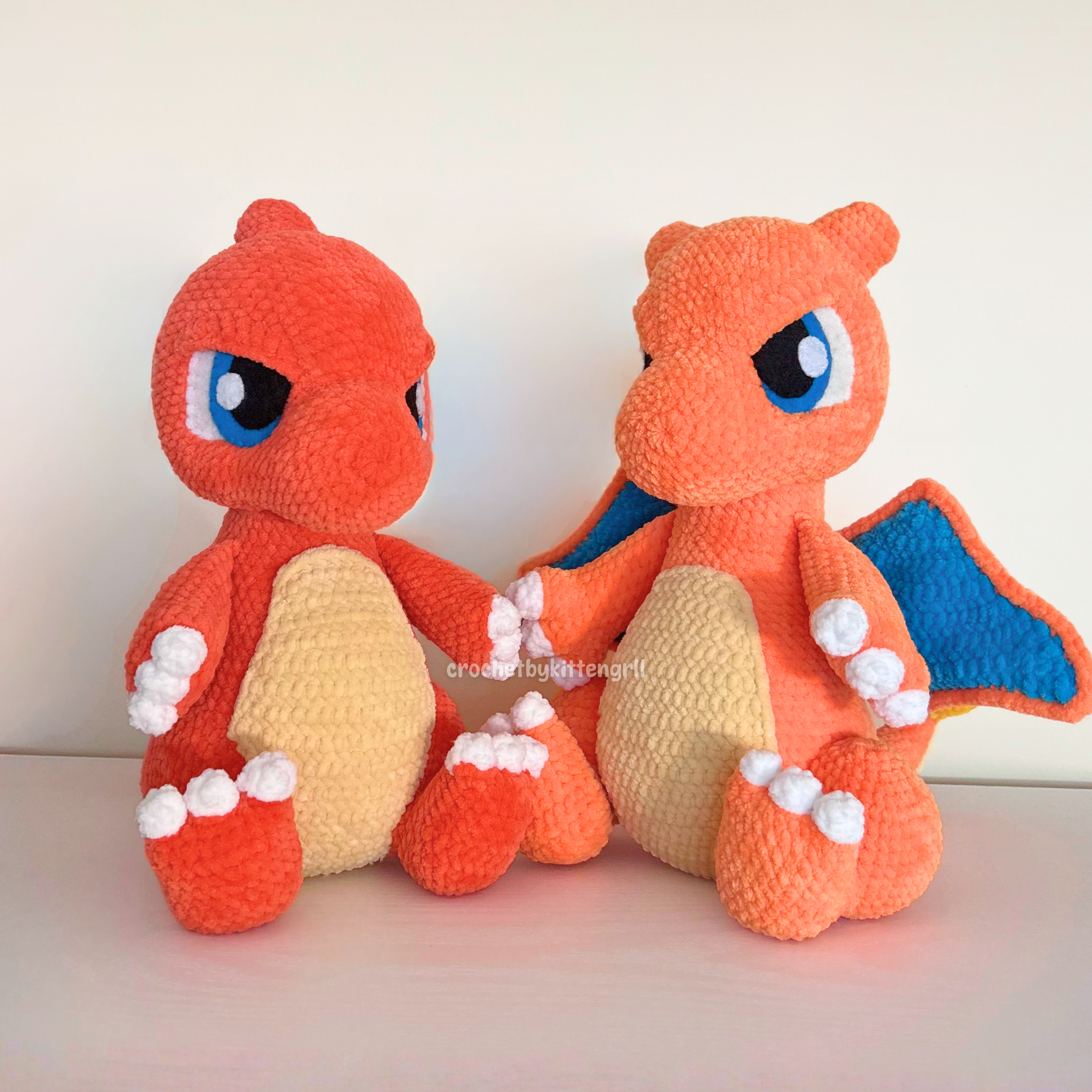 Two plush Charmander toys holding hands, with a white background.