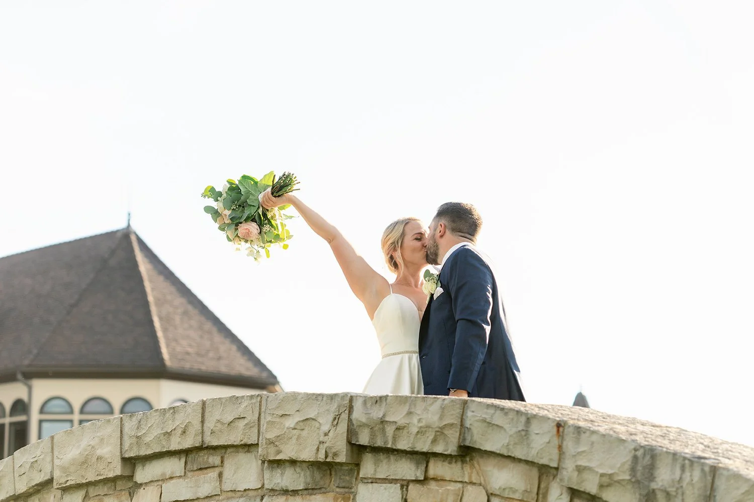 couple kisses on bridge at mistwood golf club