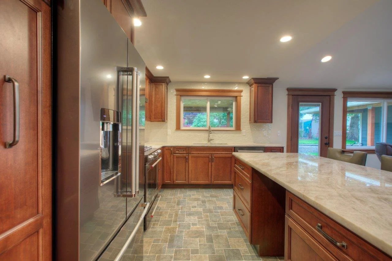Open kitchen design featuring custom wood cabinetry and stone countertops in Tacoma.