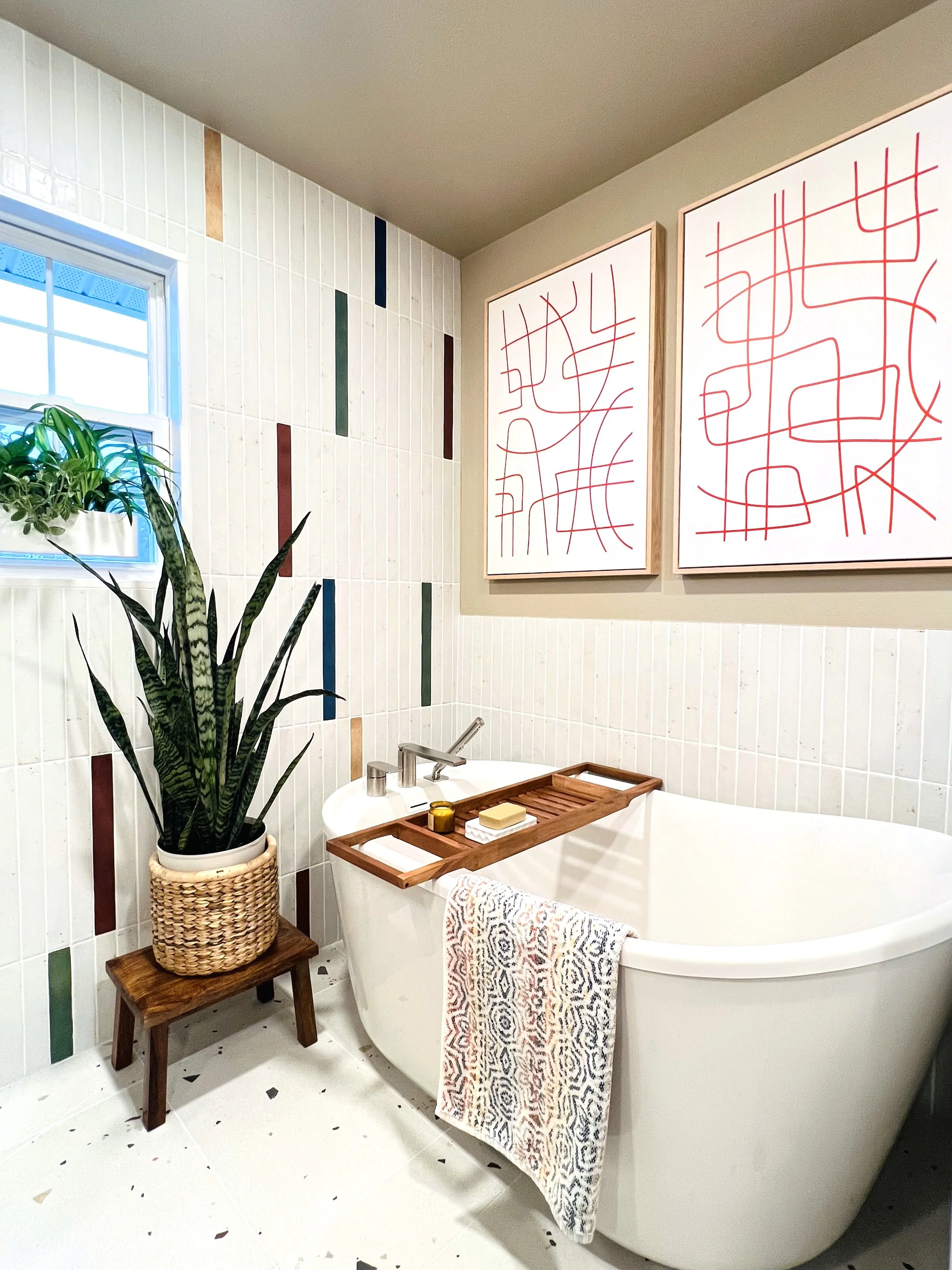 Interior design of a bold, colorful bathroom featuring striped walls, potted plants, and pink abstract art in Gig Harbor.