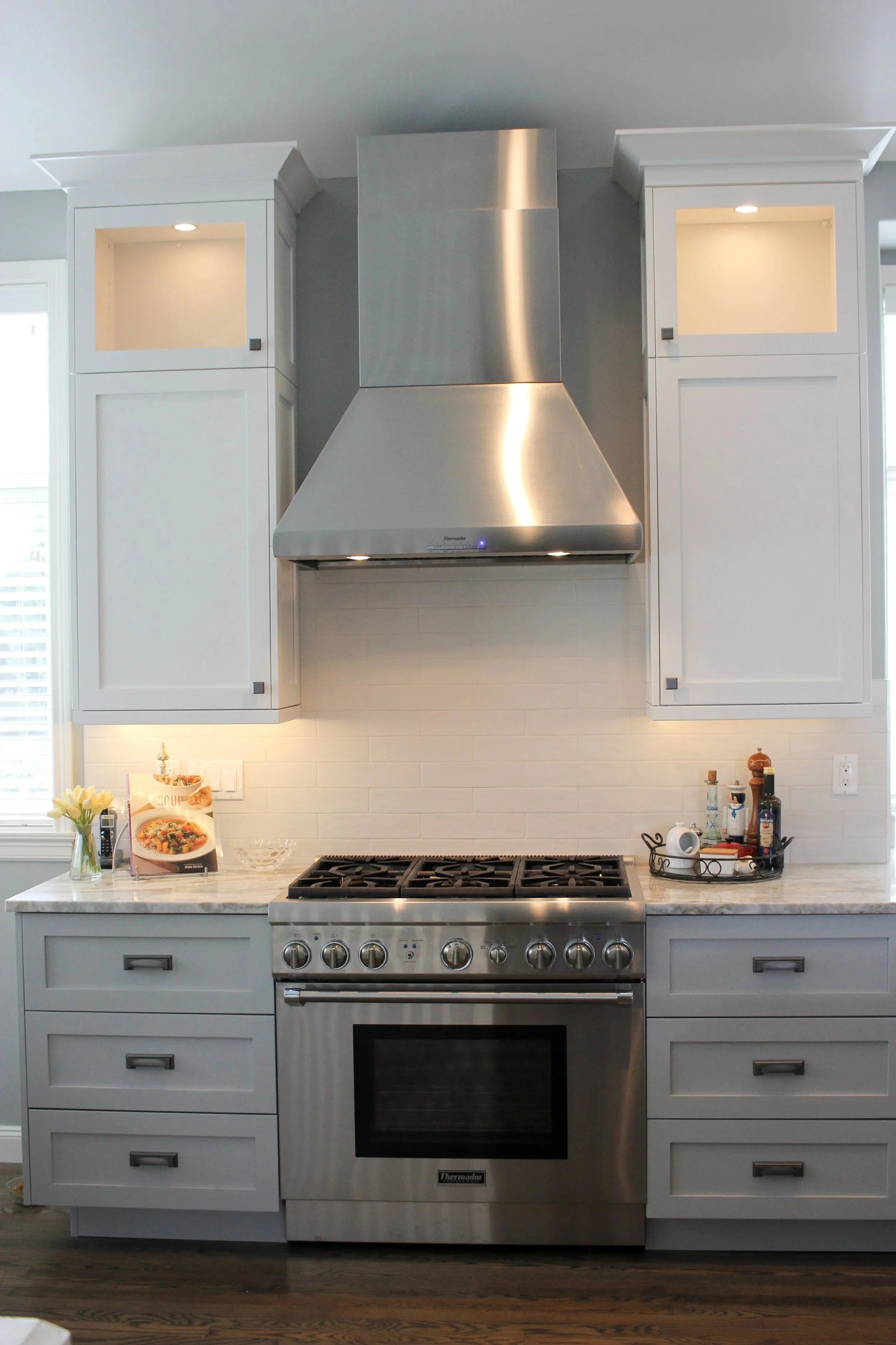 Stainless steel range hood and illuminated custom wall cabinets in University Place.