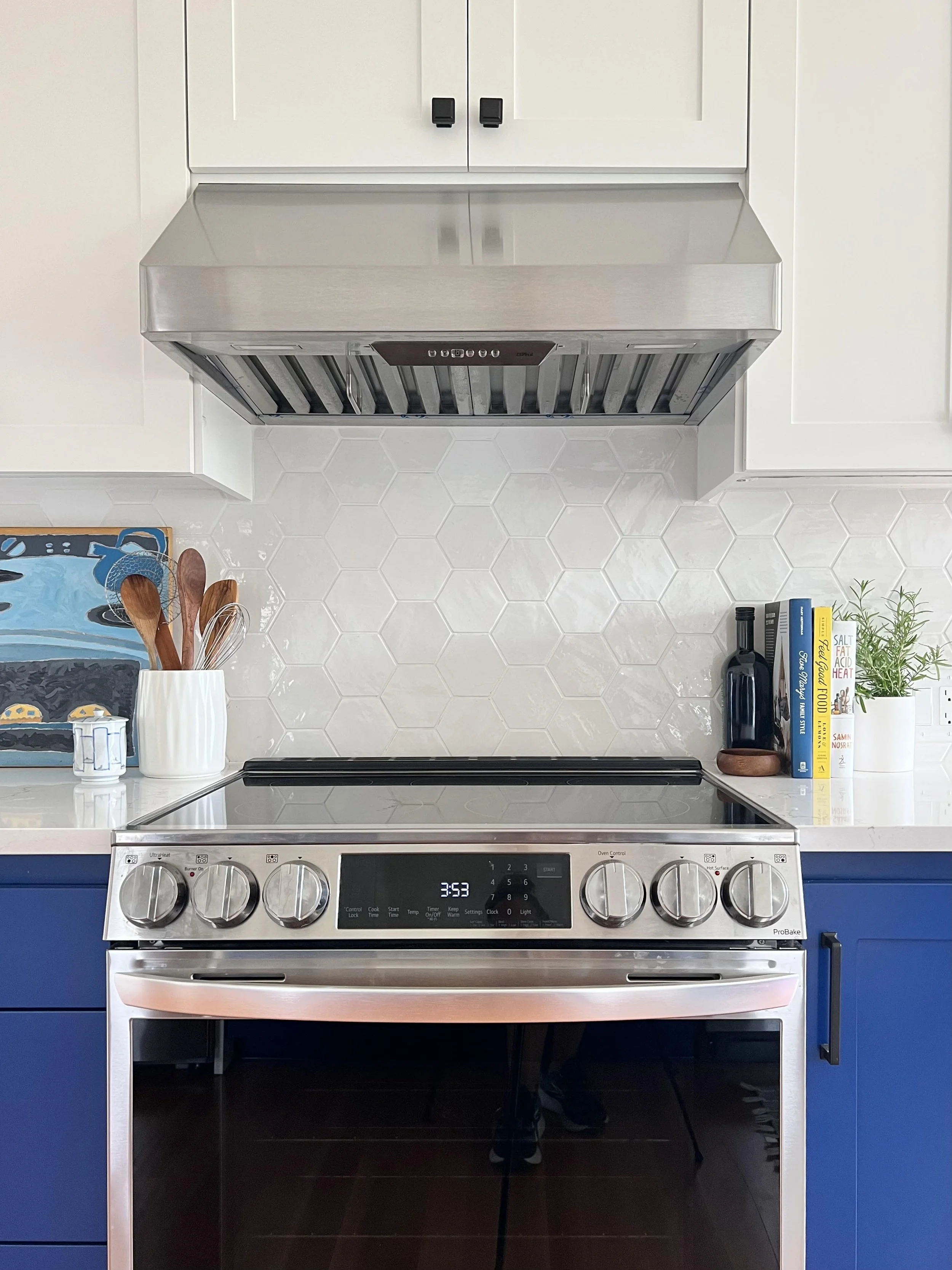 Modern kitchen remodel in Tacoma featuring bold blue lower cabinets, a stainless steel range, and custom hex tile backsplash.