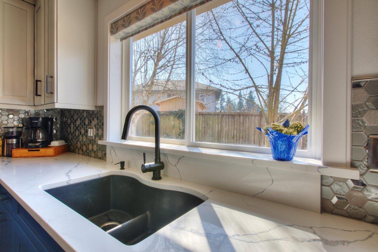 Under-mount dark basin kitchen sink with a modern black faucet and window view in a Gig Harbor remodel.