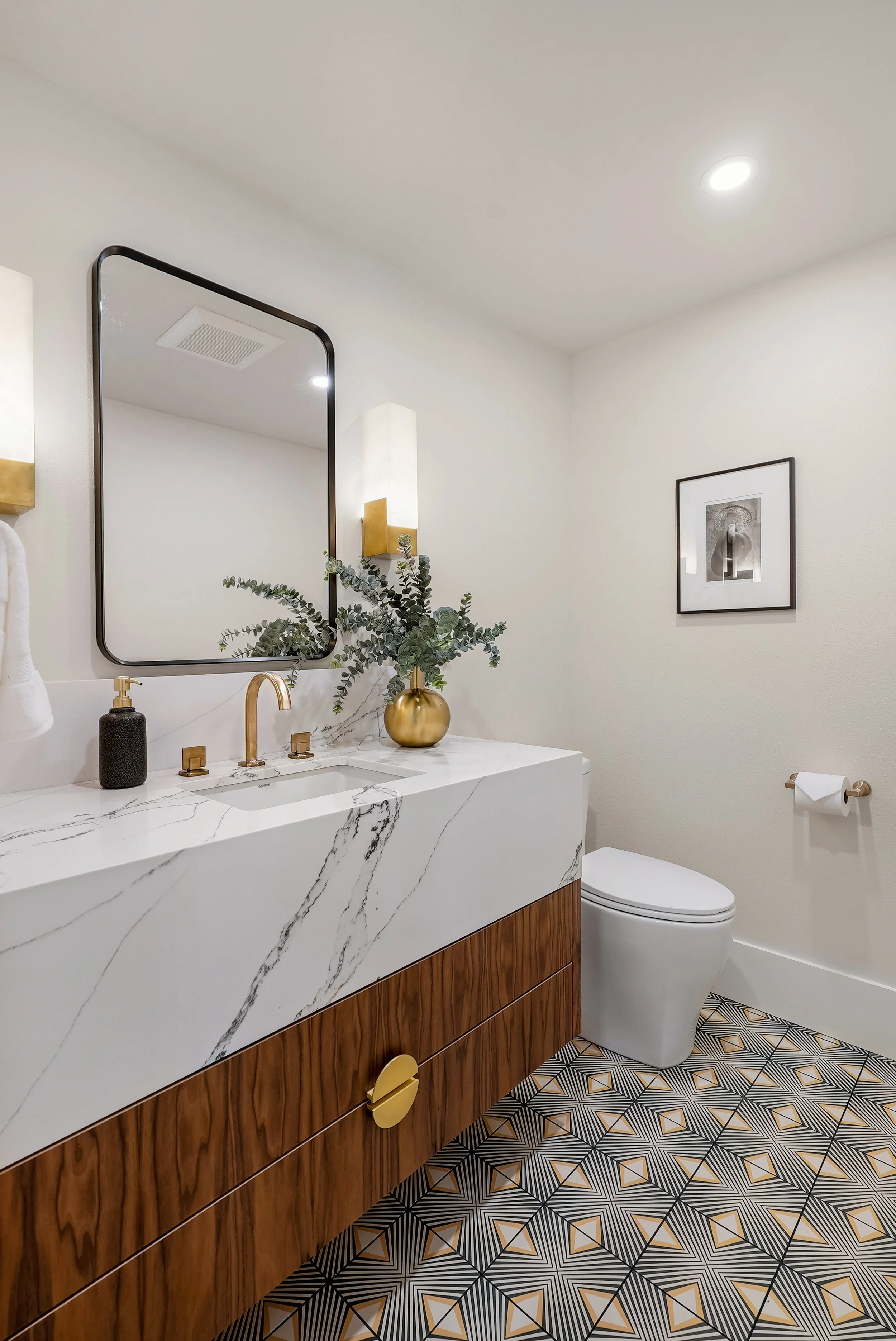 Modern powder room remodel featuring a floating wood vanity with a thick marble countertop, gold fixtures, and geometric floor tile in a Tacoma home.
