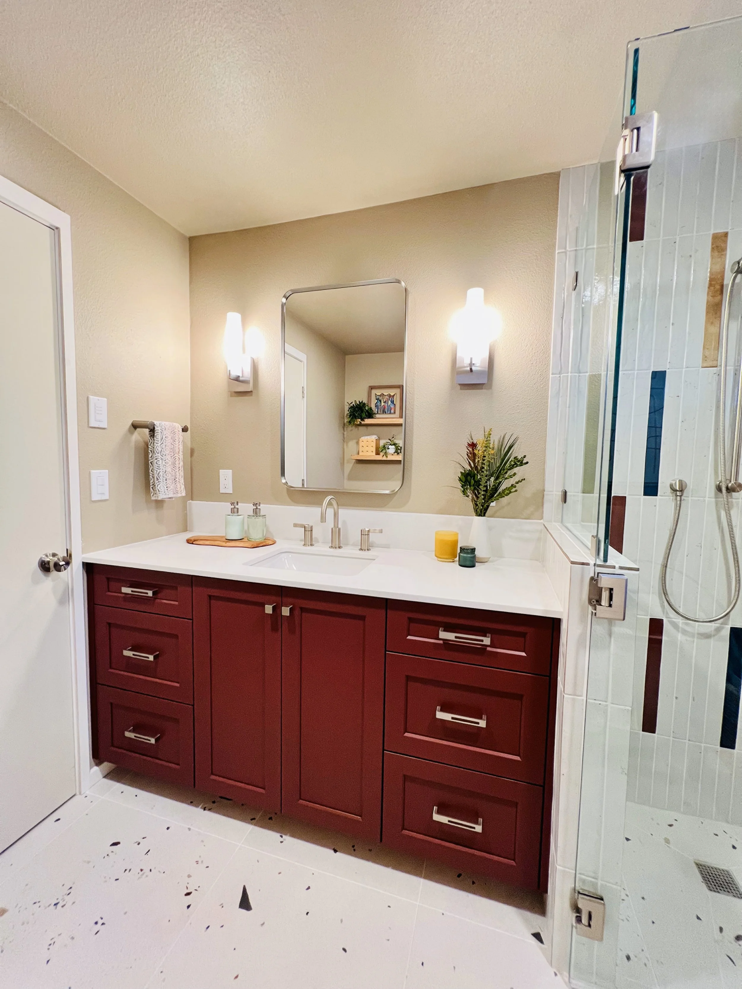 Wide view of a full bathroom remodel showing a custom vanity, modern wall sconces, and glass shower in Tacoma.