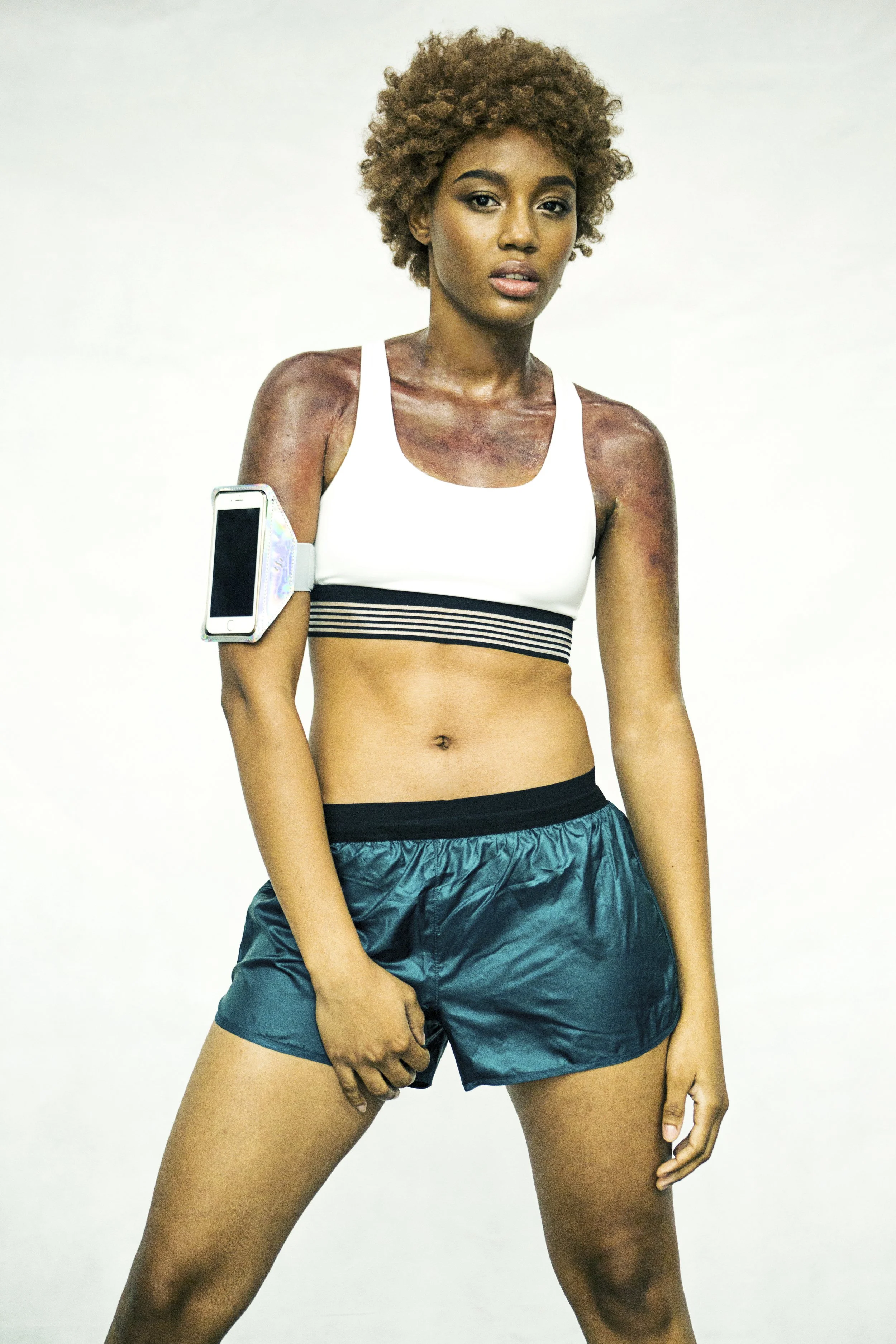 ANTI-SWEAT SKIN - From Speculative Design research TECHOSMETICS & THE SYNTHETIC SKIN SALON. A woman wearing workout clothes with ACTIVATED ANTI-SWEAT SKIN on her shoulders and arms.