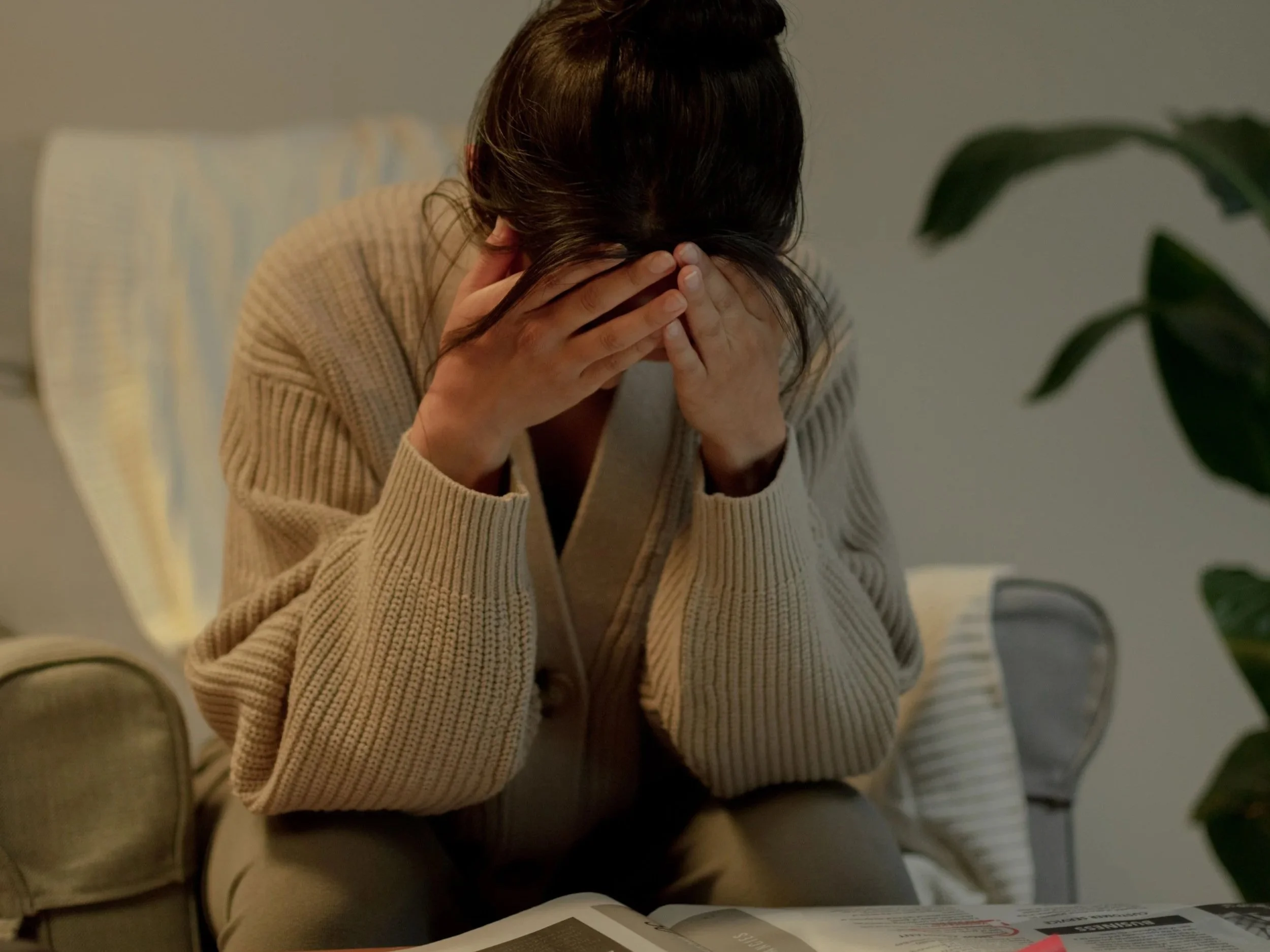 woman on sofa stressed with head in hands