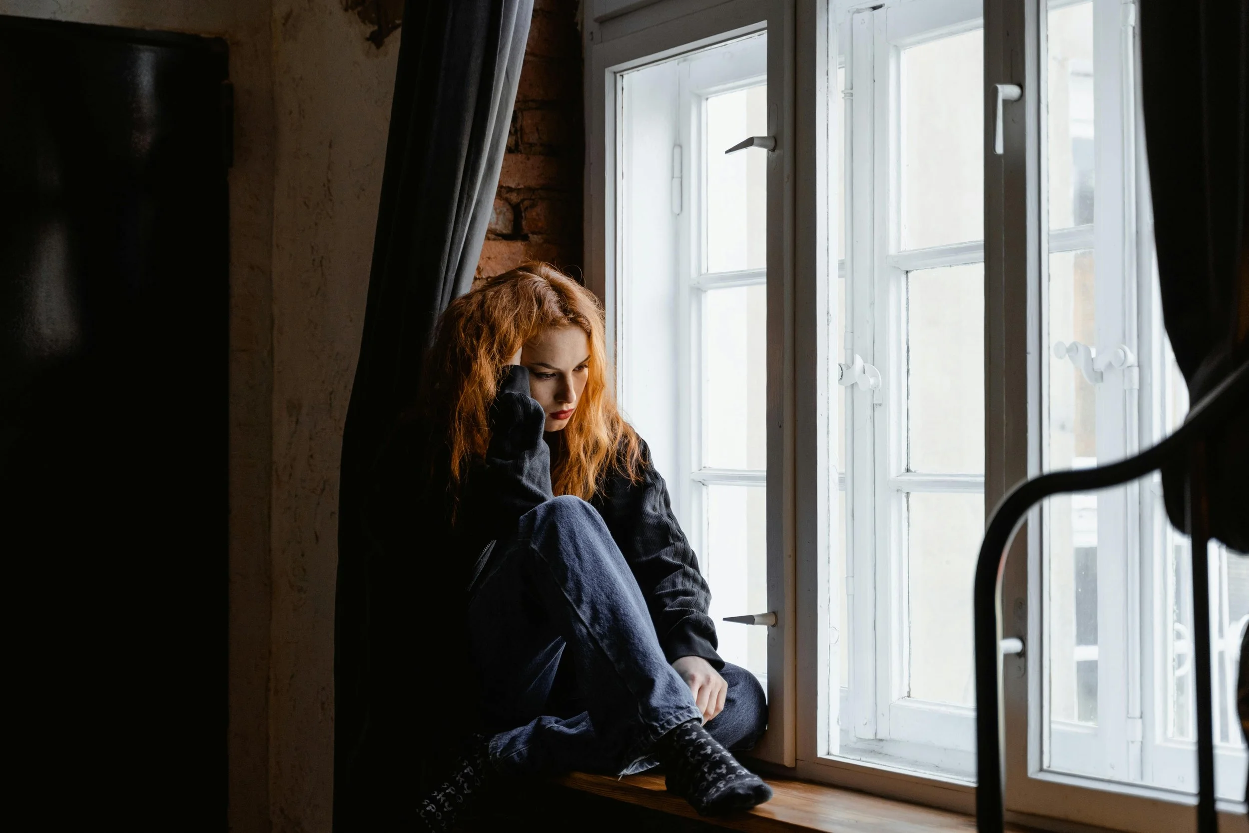 grieving woman sitting in window