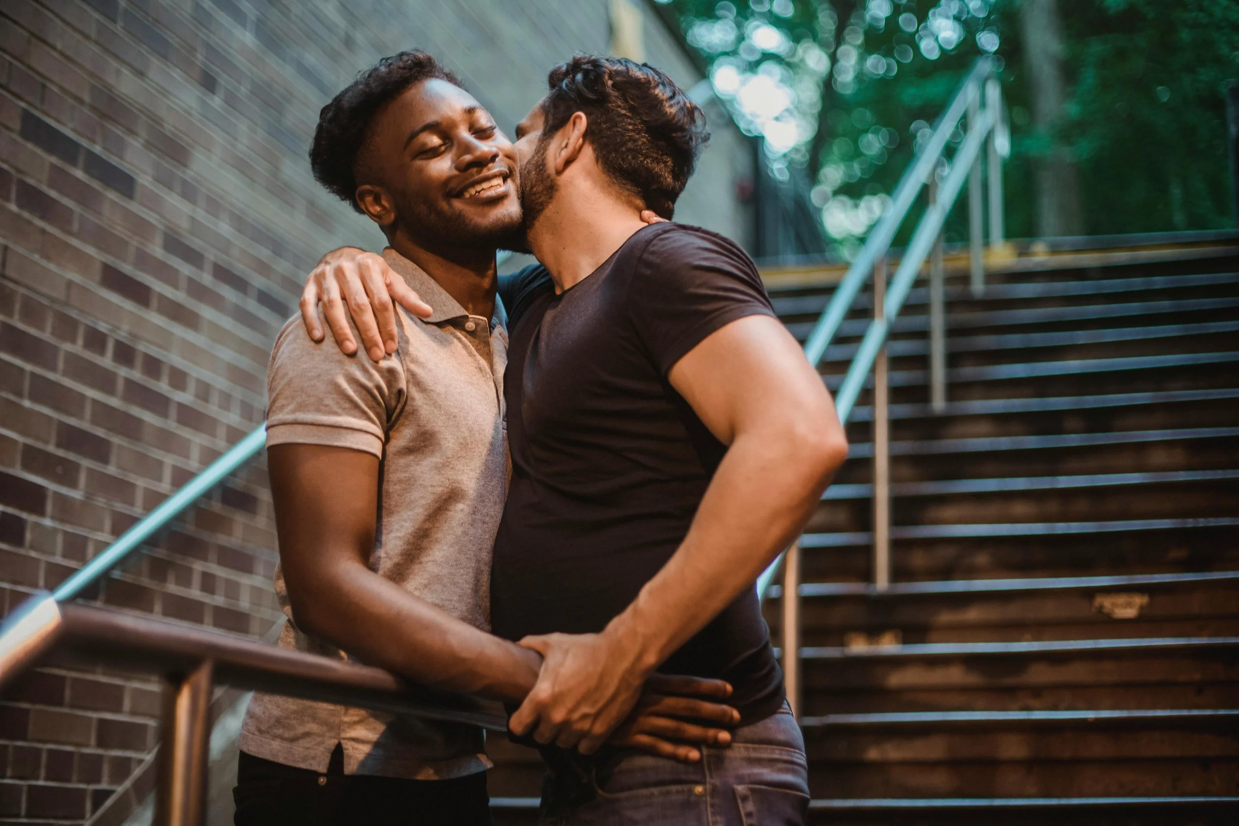 two men kissing on stairs smiling