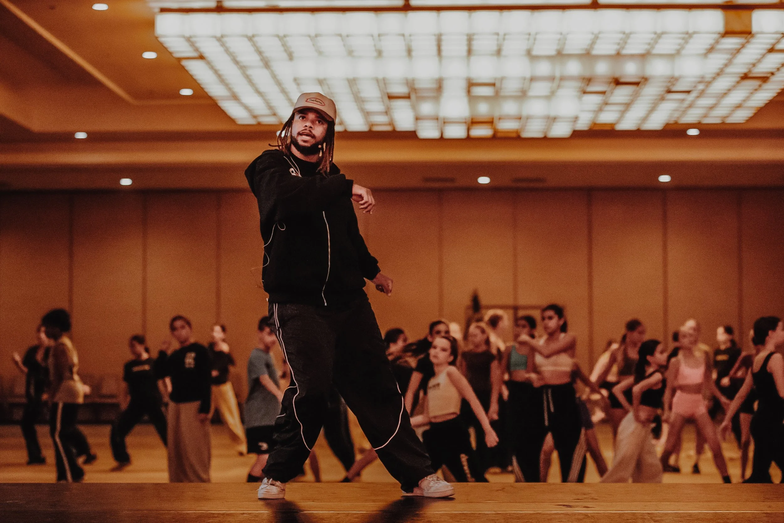 A man with long hair and a beard wears a black shirt, arms outstretched, with lightning in the background and a bright light source behind him.