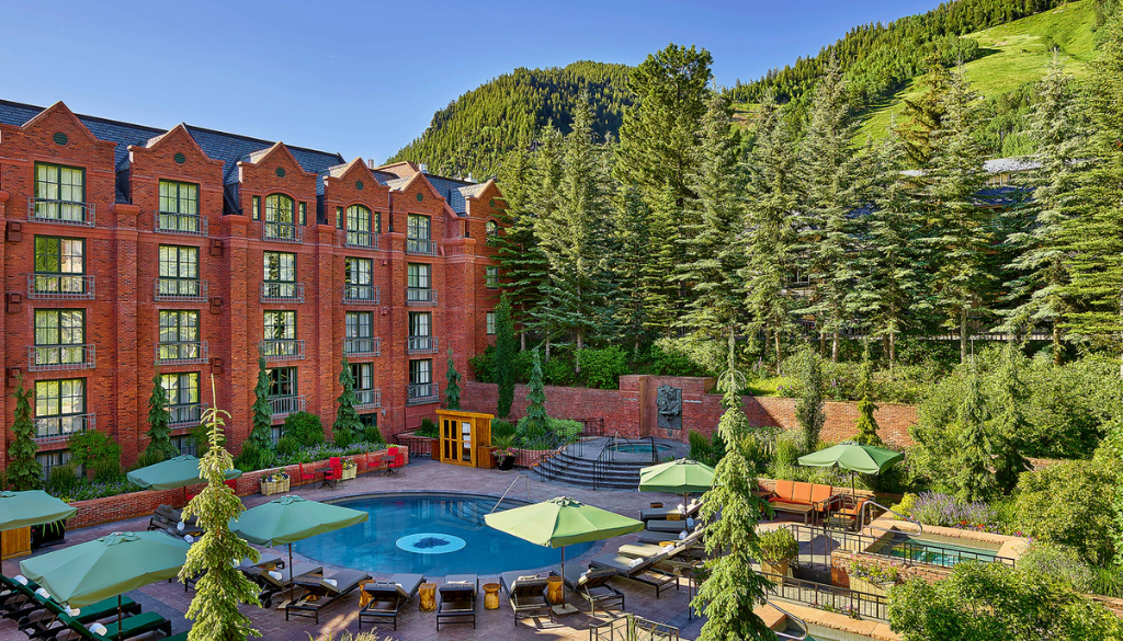 St. Regis Aspen resort outdoor swimming pool area with green lounge chairs and umbrellas in summer