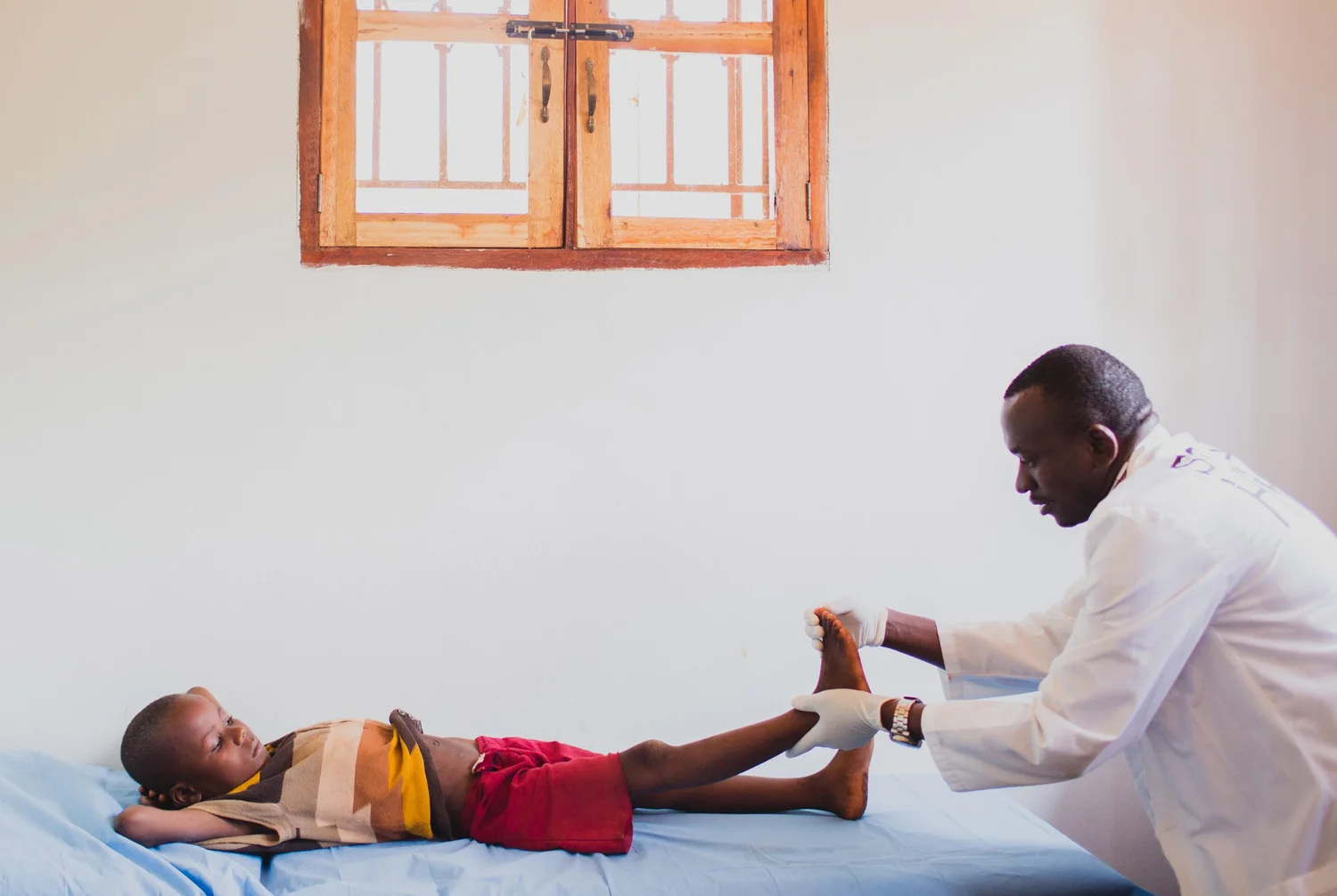 Medical worker inspecting feet during jigger care in a Ugandan clinic through Sole Hope