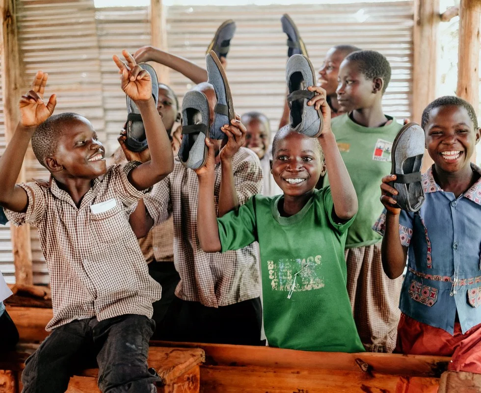 Sole Hope team member fitting protective shoes on a child in Uganda