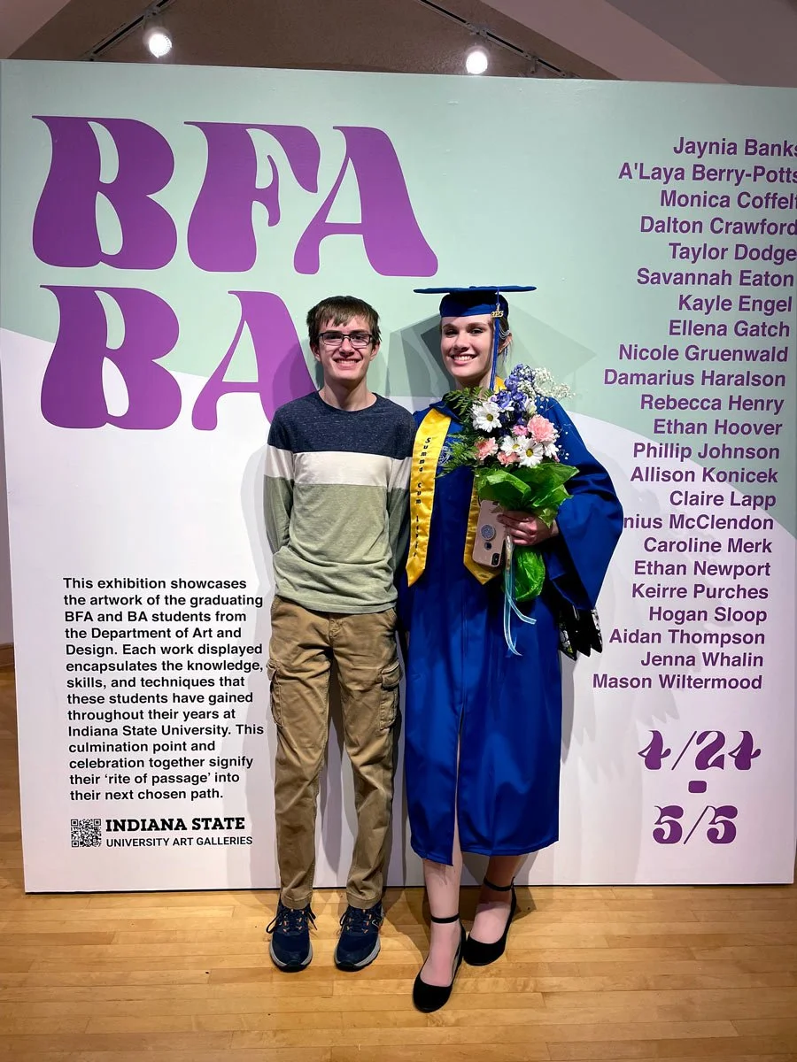 Caroline and her brother standing in front of a moveable wall that says BFA BA.