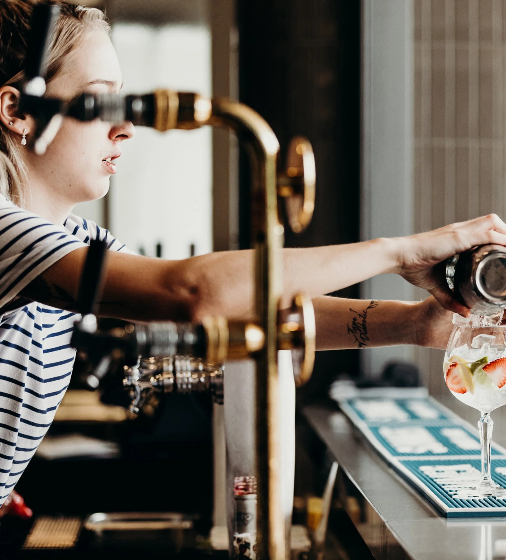 Bartender pouring a cocktail into a glass with ice and fruit slices