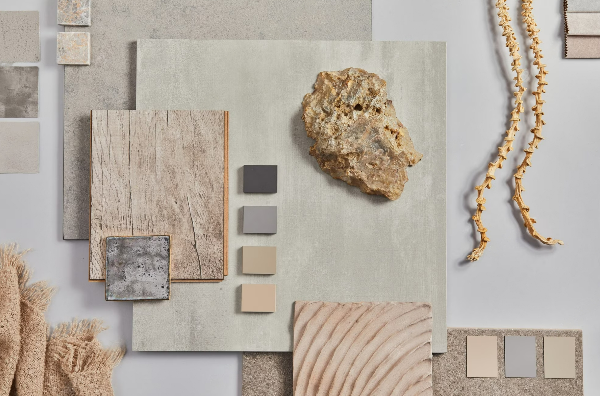 mood board flatlay featuring neutral paint colour swatches in charcoal, grey, sand and beige tones, timber flooring samples, a raw stone specimen, and textured fabric swatch — material and colour palette inspiration by The Home Studio Co