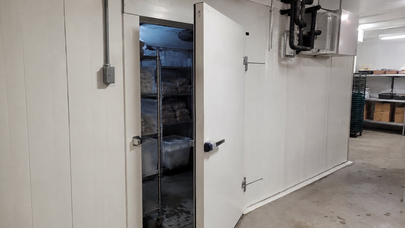 Commercial walk-in freezer with open door in a food business warehouse