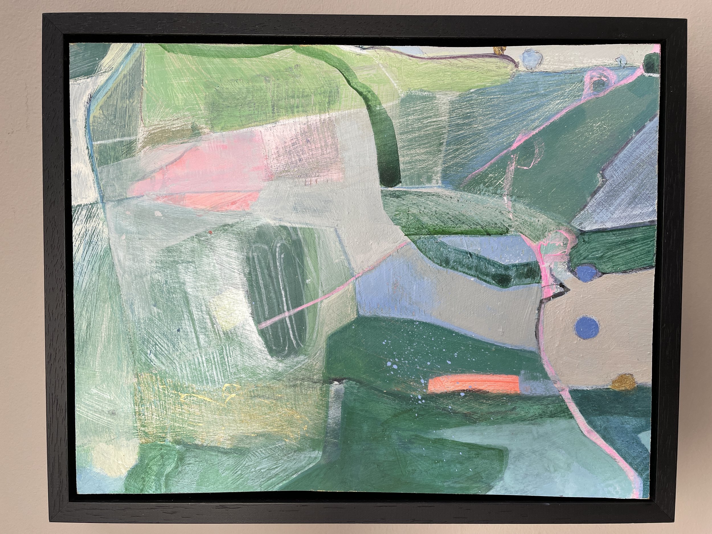 Abstract painting with green, pink, blue, and gray colors, framed in black, hung on a wall.
