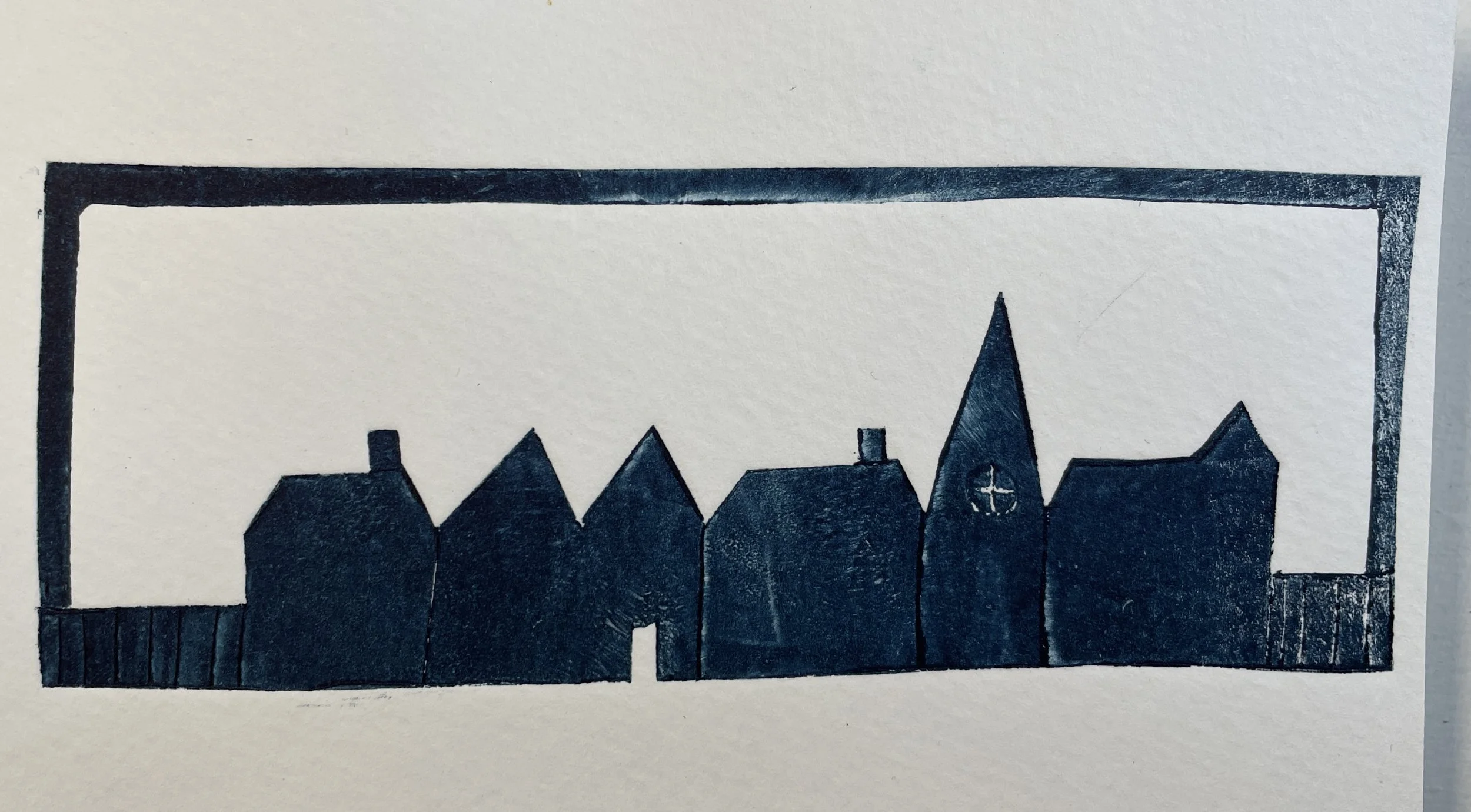 Black silhouette of a row of houses, including one with a steeple and cross, inside a rectangular frame.