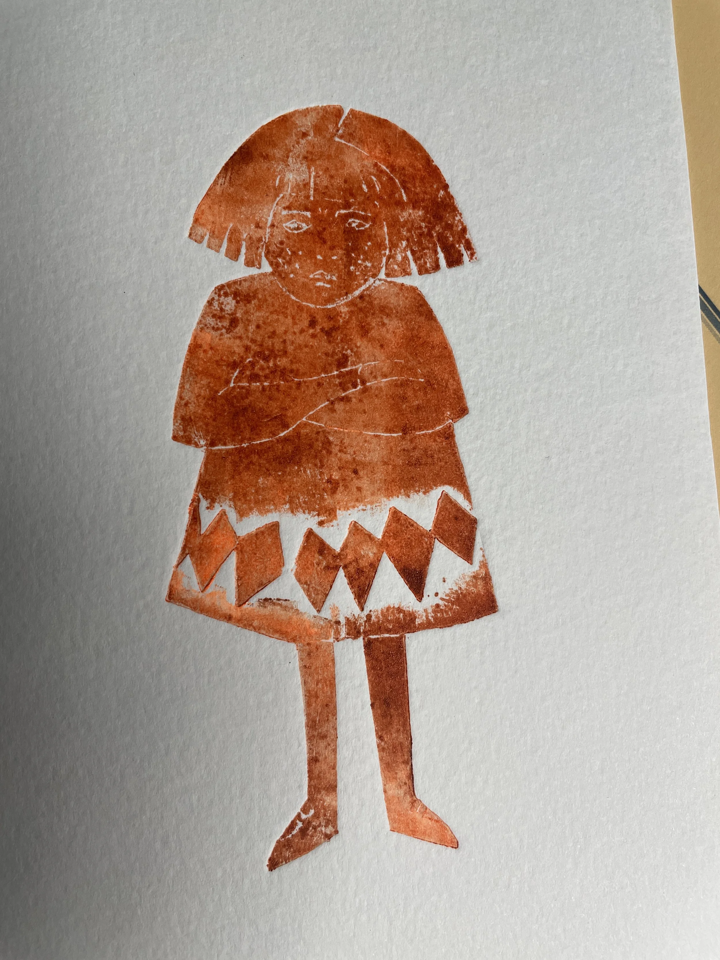 Red rubber stamp of a girl with short hair, crossed arms, wearing a dress with zigzag pattern.