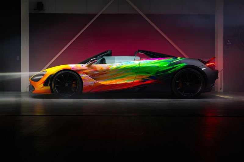 A colorful sports car with a rainbow paint job inside a dimly lit showroom.