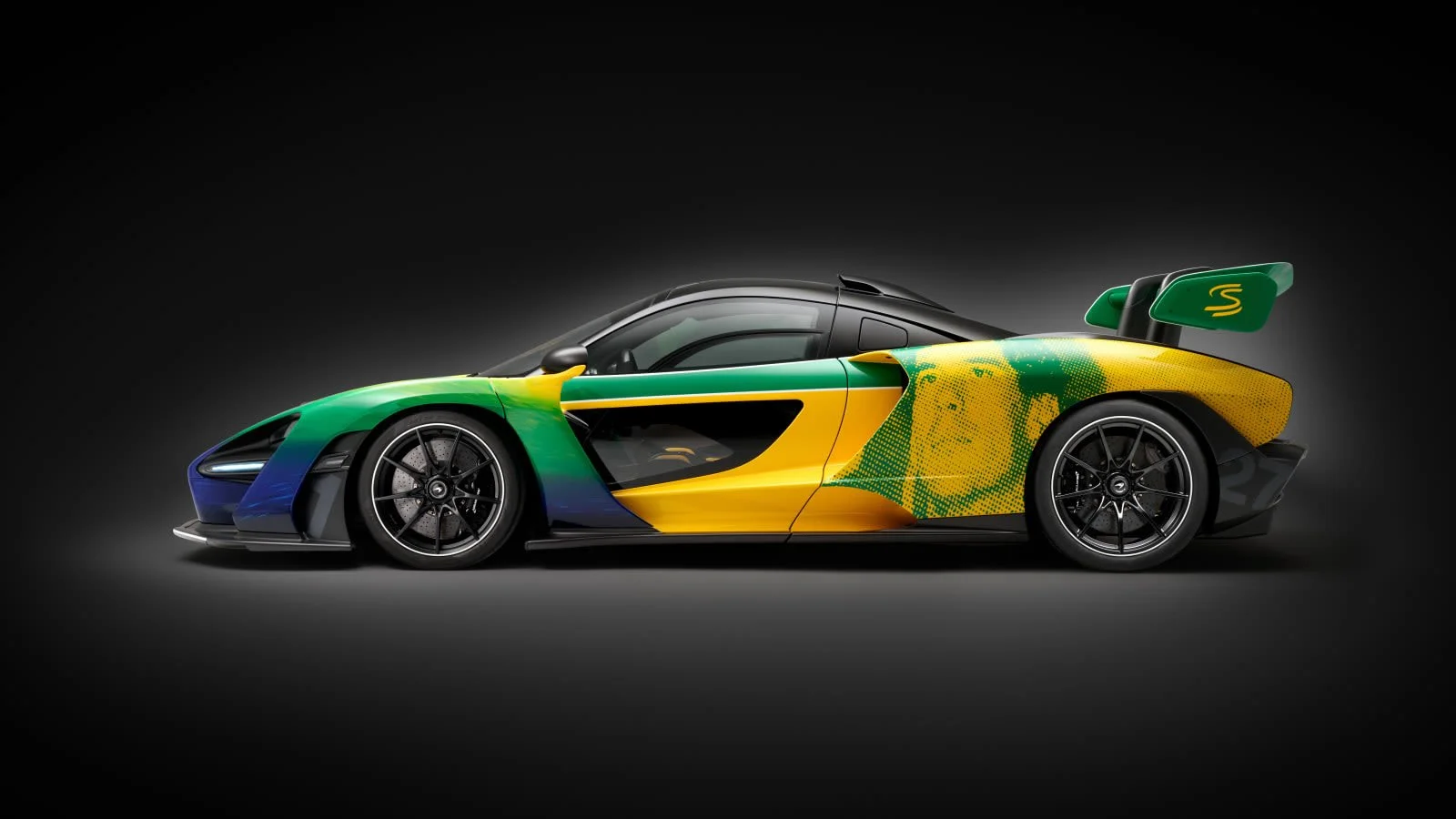 A sleek world-record-holding racing car with a colorful green, yellow, and black Brazil flag-inspired design, set against a black background.